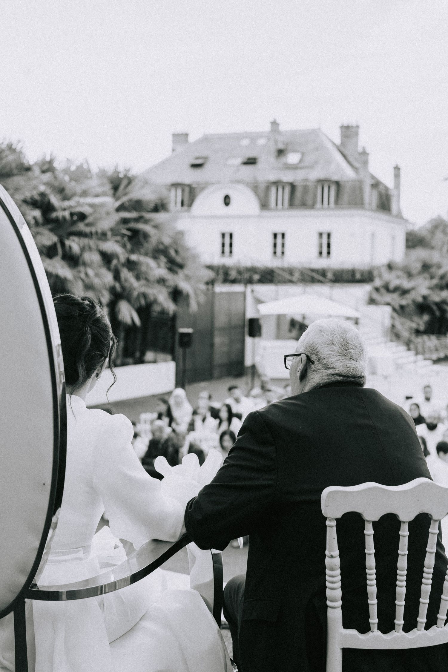 Black and white photo of wedding celebration viewed from behind seated musician.