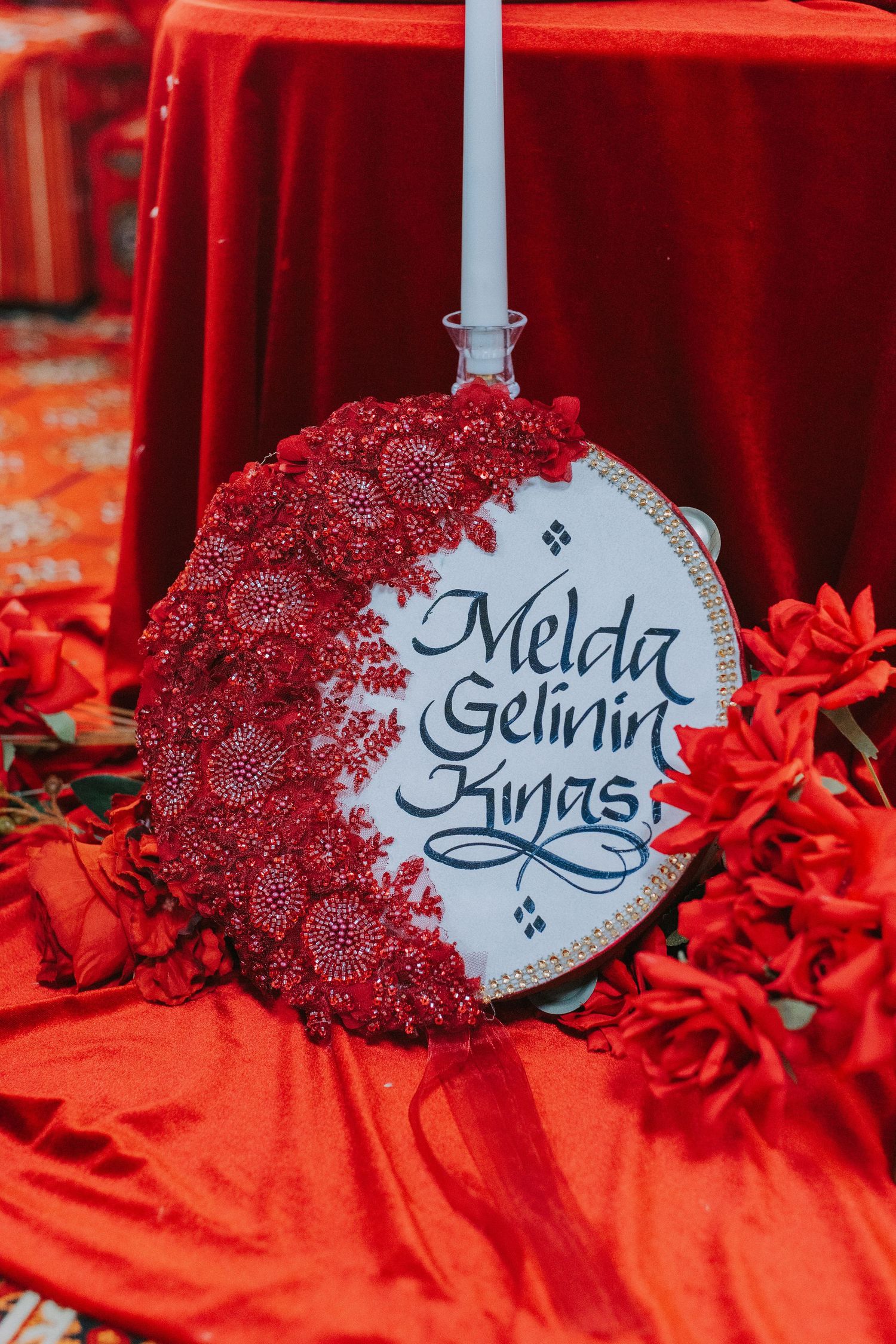 Decorative circular wedding sign with red lace details against red velvet background.