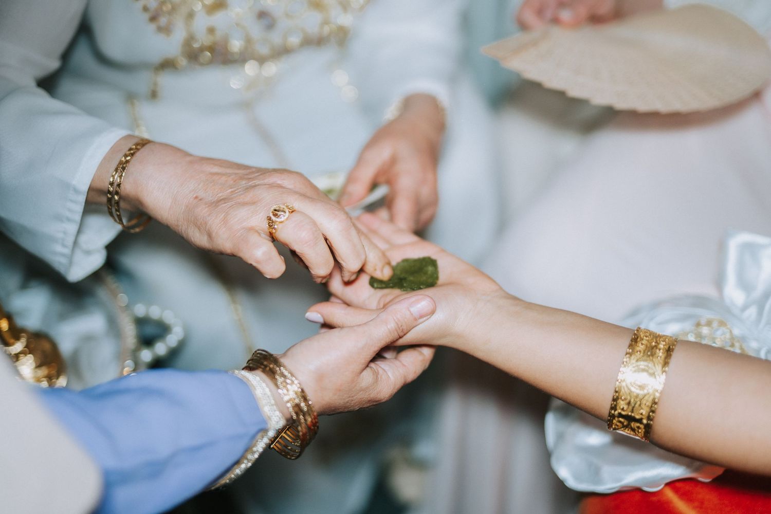 Close-up shot of hands with gold jewelry and bracelets during a traditional ceremony ritual.