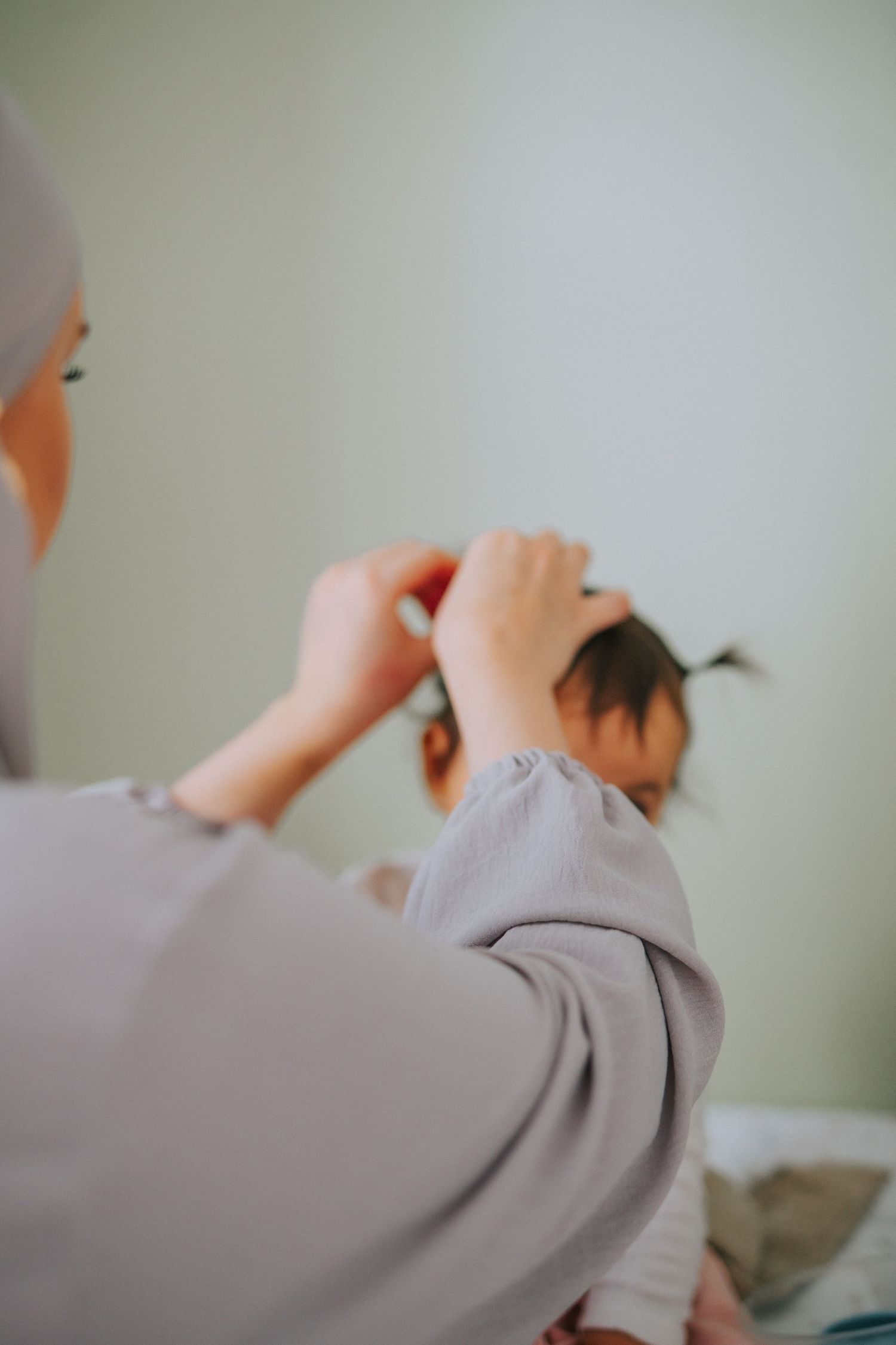 Hands styling hair against a soft beige background.