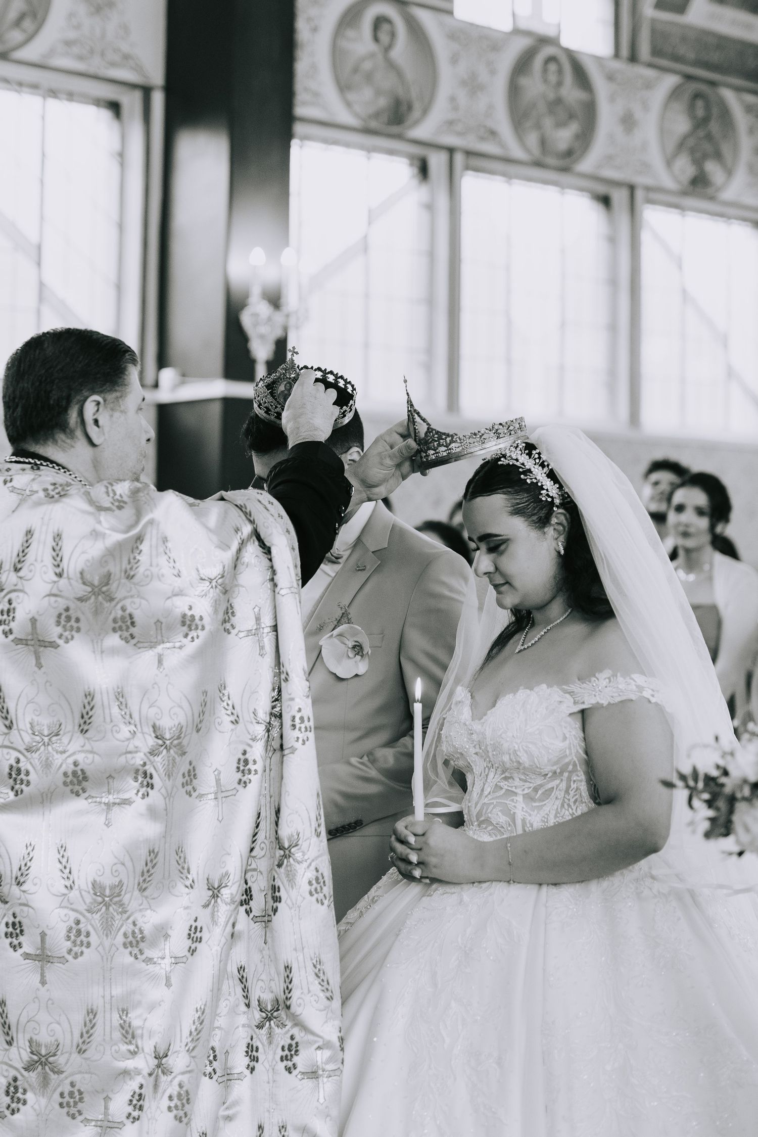 A traditional religious wedding ceremony in progress with a bride in a white gown and veil receiving blessings.