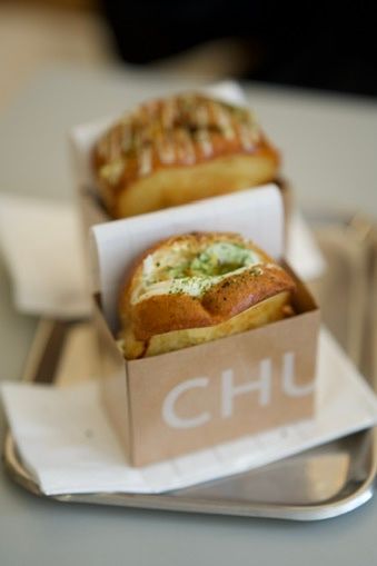 Two gourmet burgers served in branded CHU boxes on a metal tray.