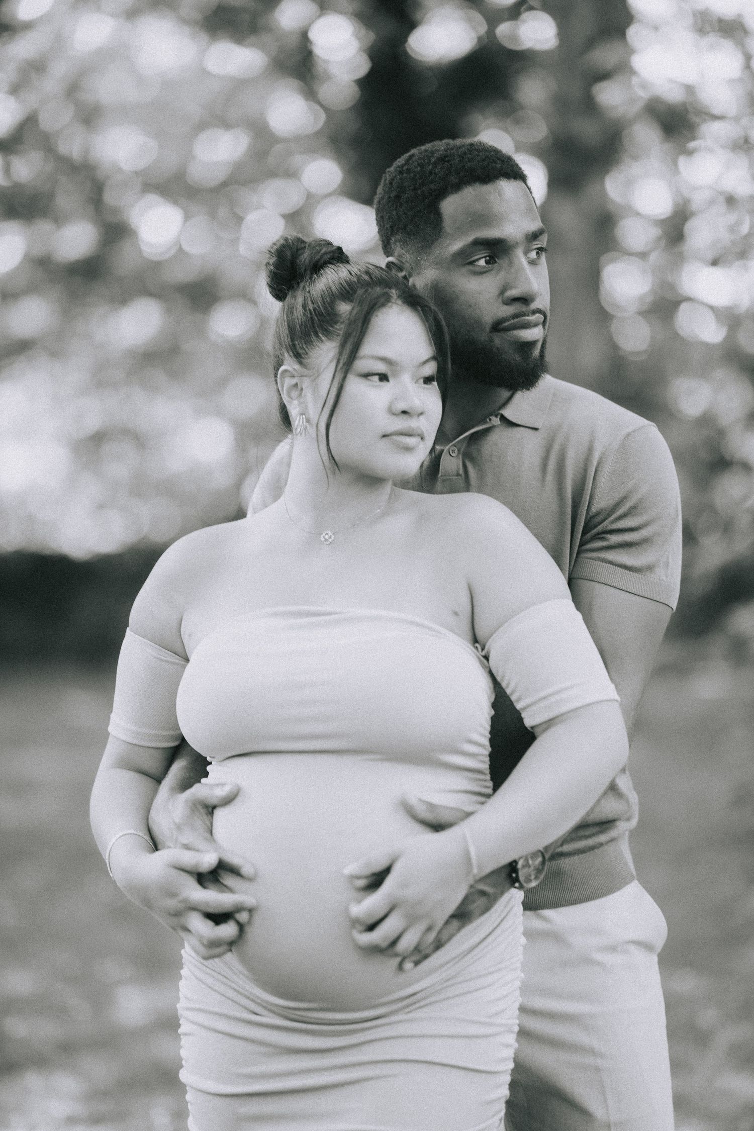 Black and white outdoor maternity photo showing a romantic embrace, with the expectant mother wearing a fitted light top.