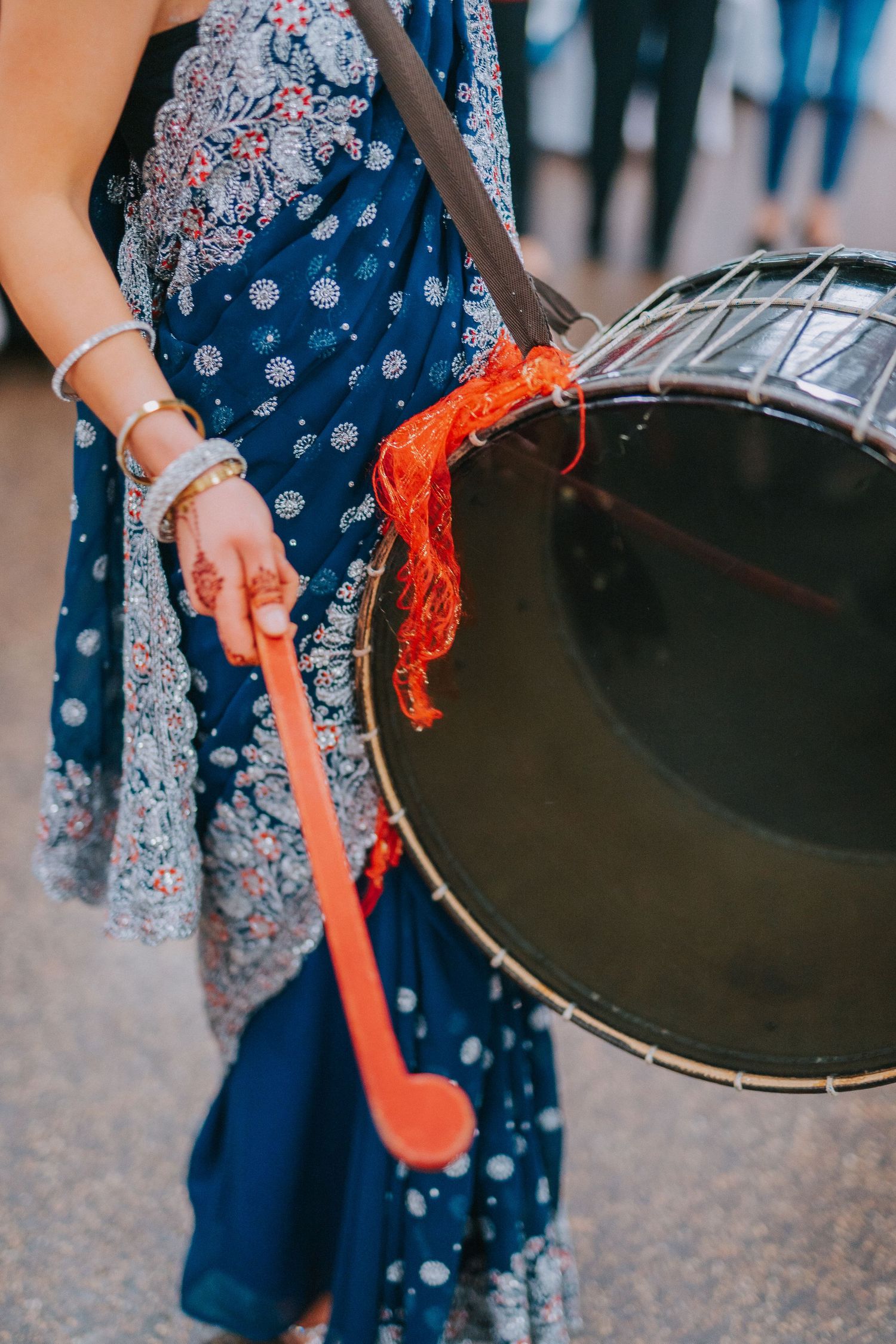 Close-up of ornate blue and silver sari with traditional drum during celebration.