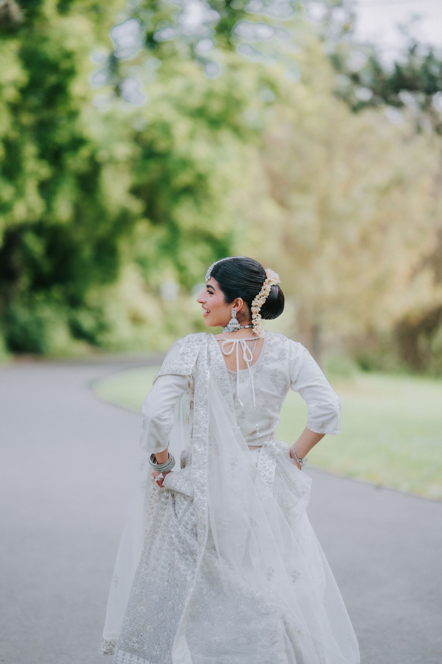 Artistic portrait of bride in white dress posing on outdoor path.