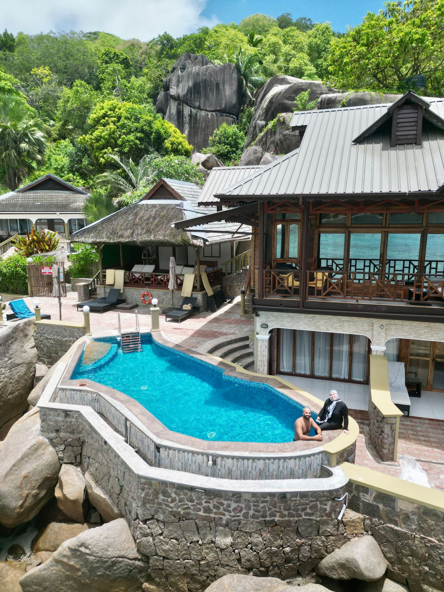 Luxury resort villa with infinity pool built into rocky hillside surrounded by tropical foliage.