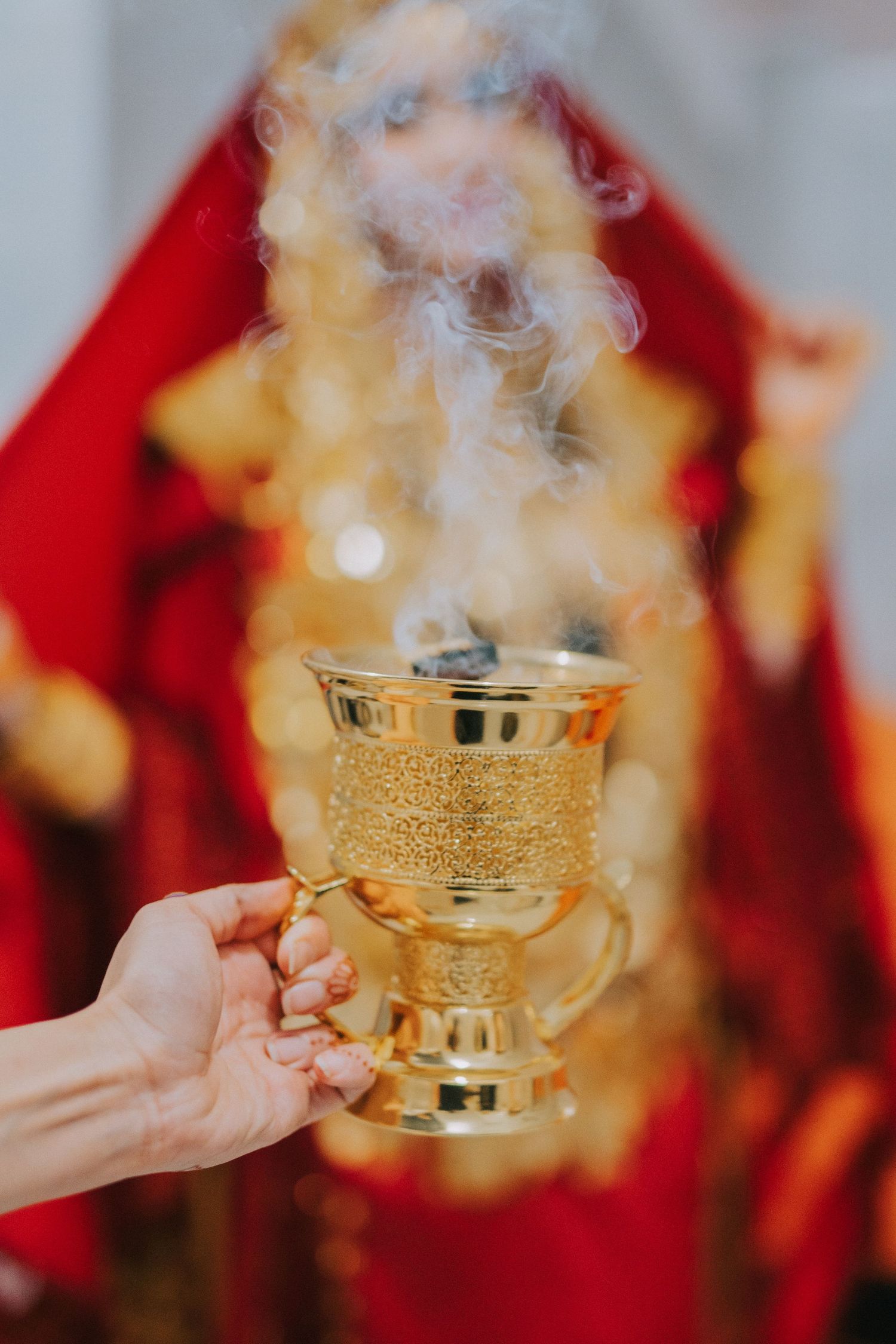 Golden incense burner with smoke rising against a red draped background.