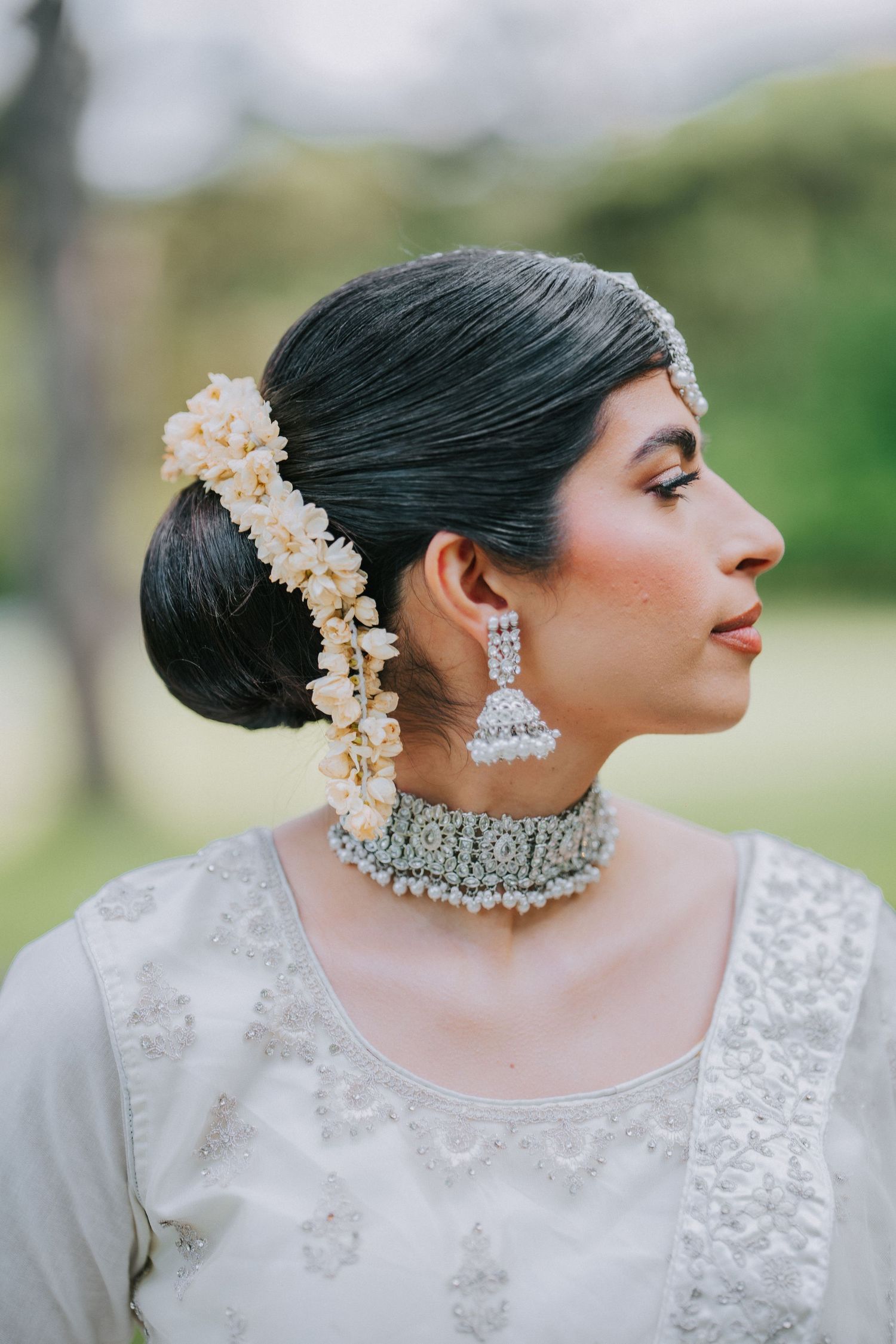 Profile view of elegant bridal look featuring crystal jewelry and floral hair accessories.