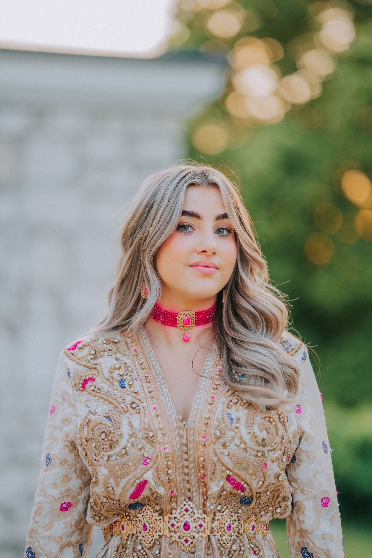 Portrait in an ornate beige and pink embroidered Moroccan dress with golden details.