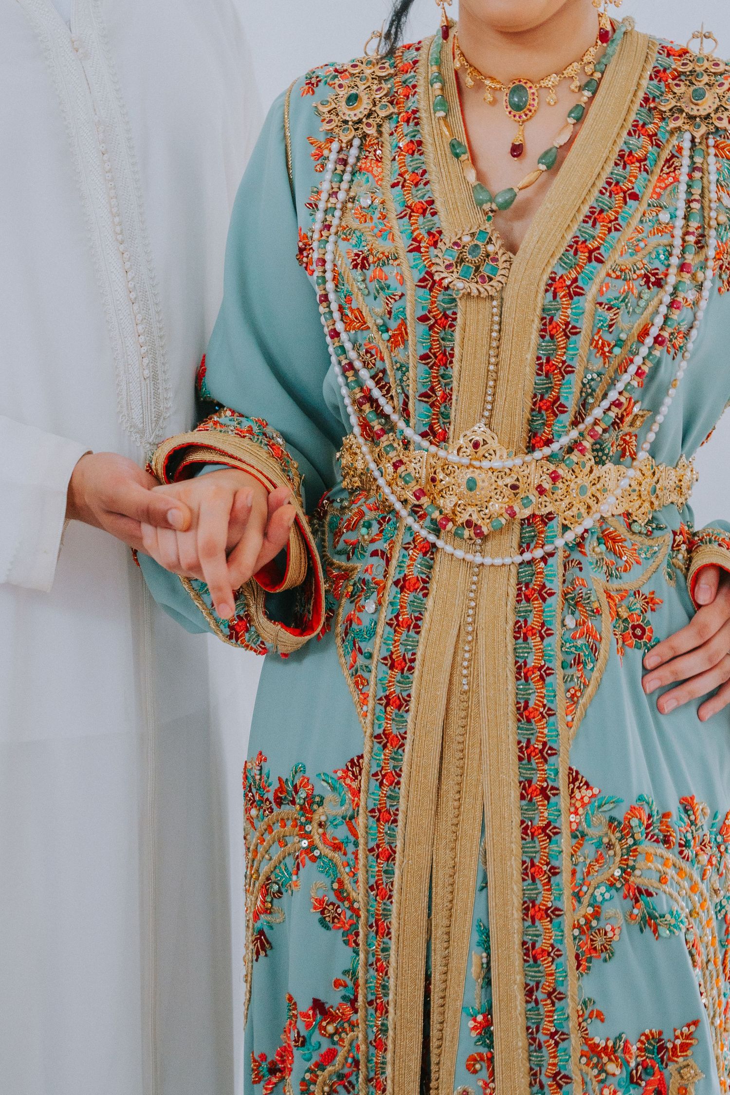 Detailed view of ornate turquoise Moroccan kaftan with intricate floral beadwork and embroidery.