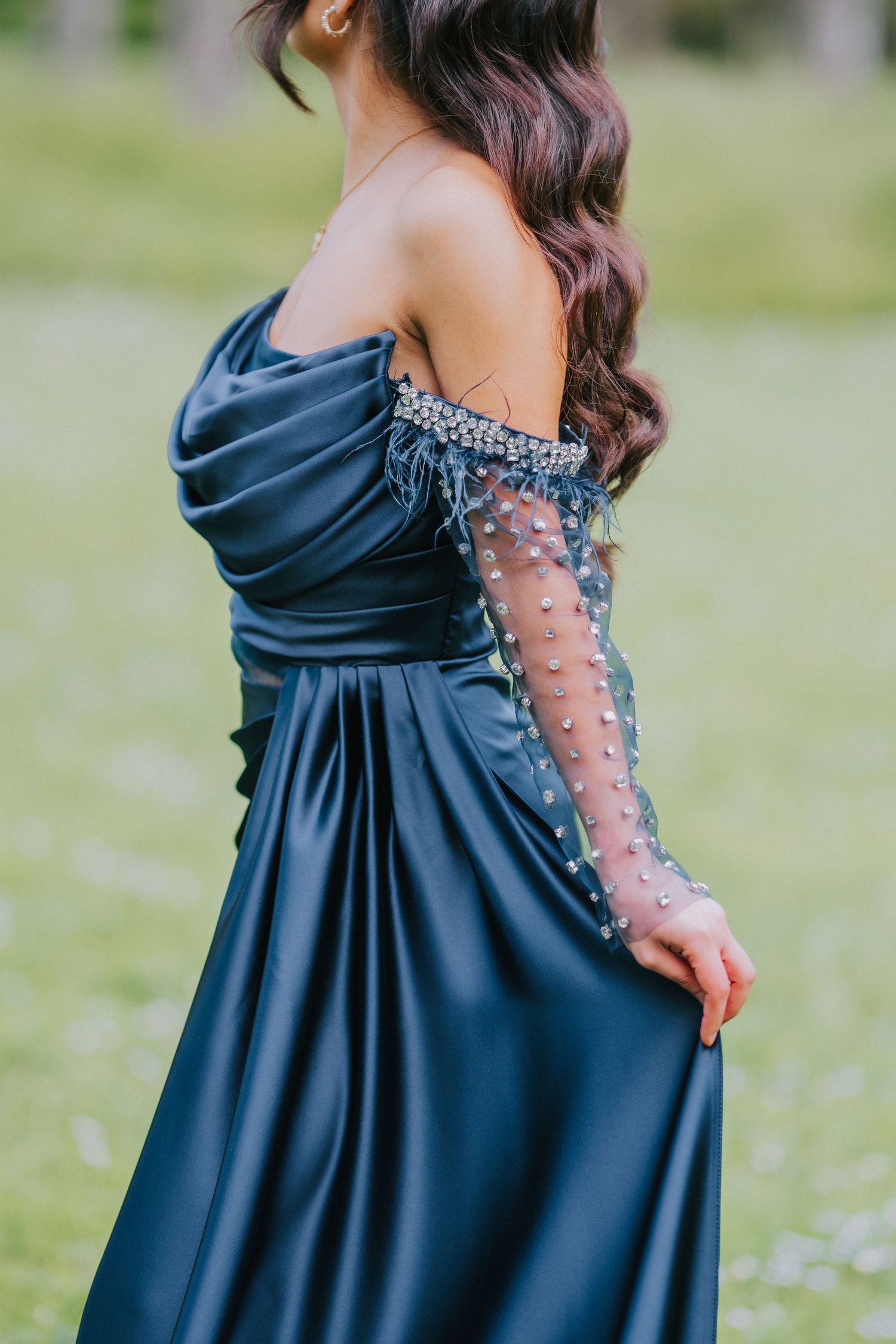 Close-up of navy blue formal dress with beaded sleeves and off-shoulder design.