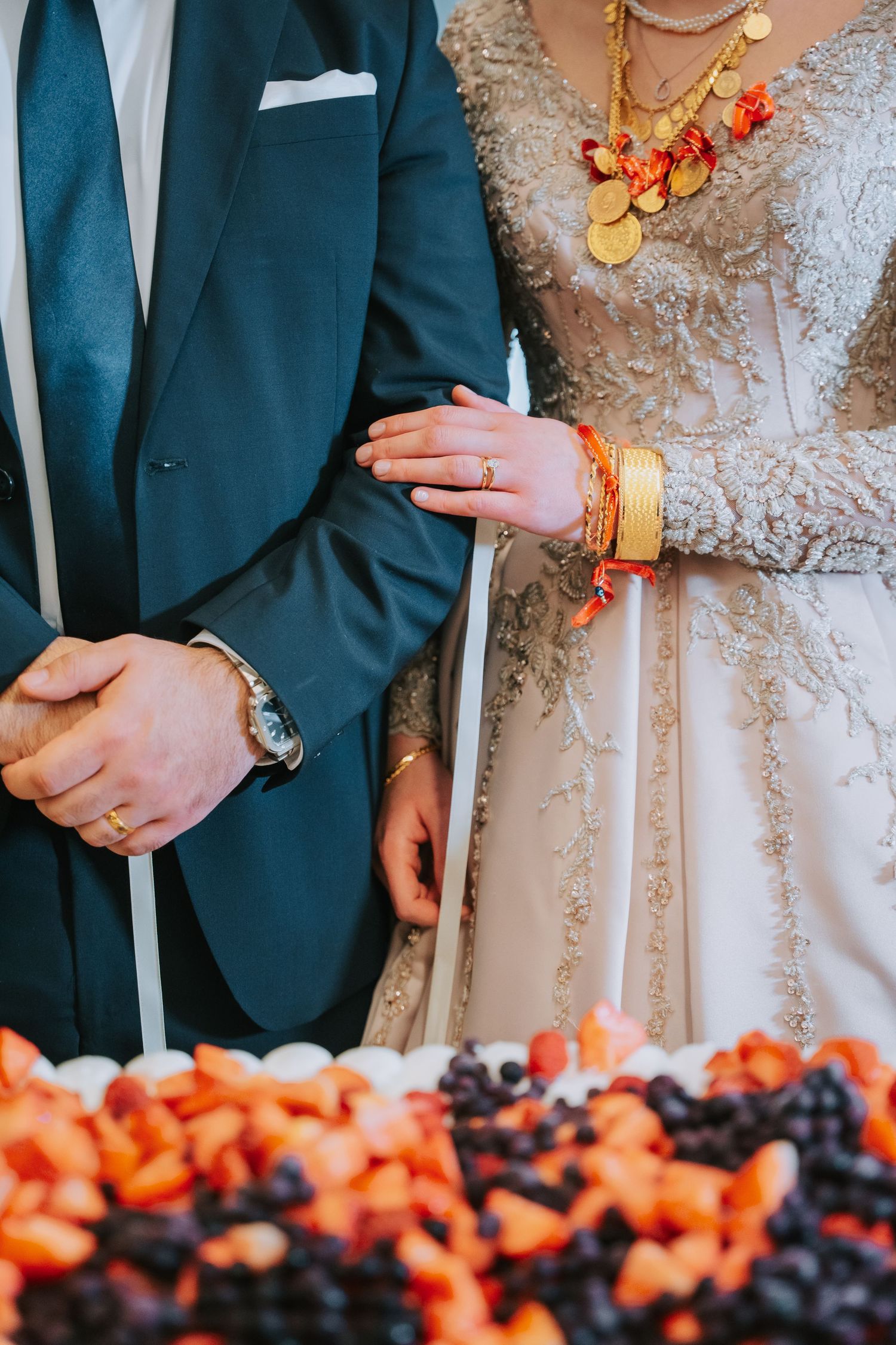 Couple in formal wear showing traditional gold jewelry and teal suit details.