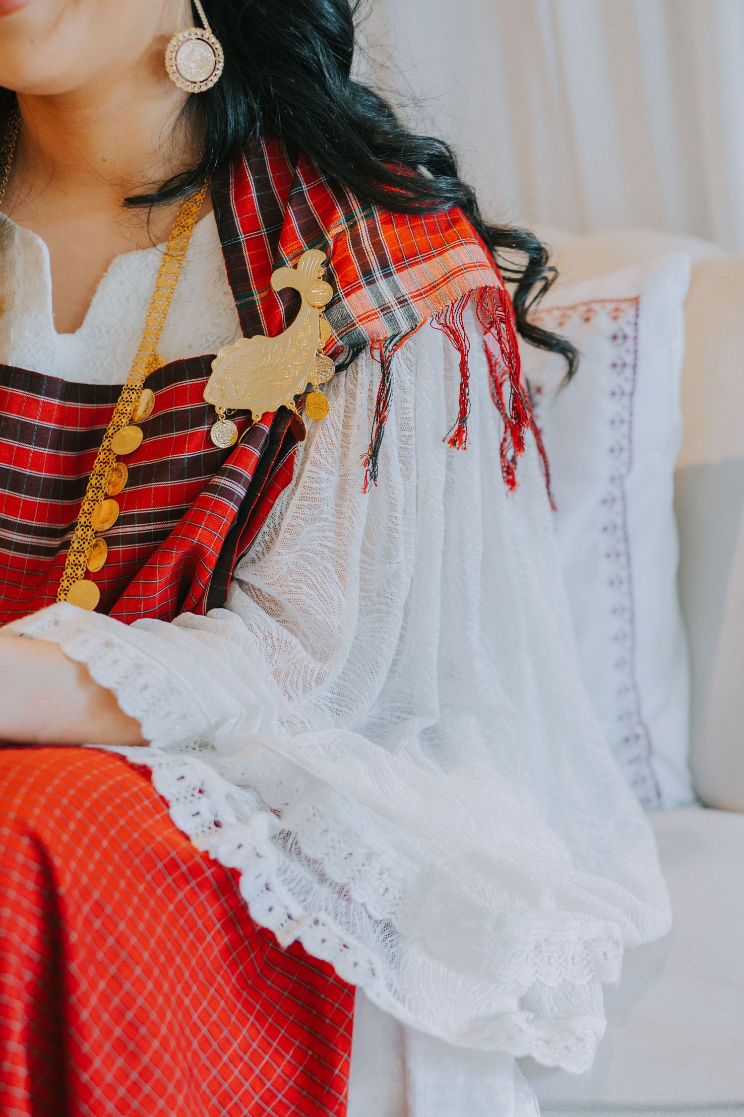 Close-up of traditional red and white dress with gold jewelry and ornate accessories.