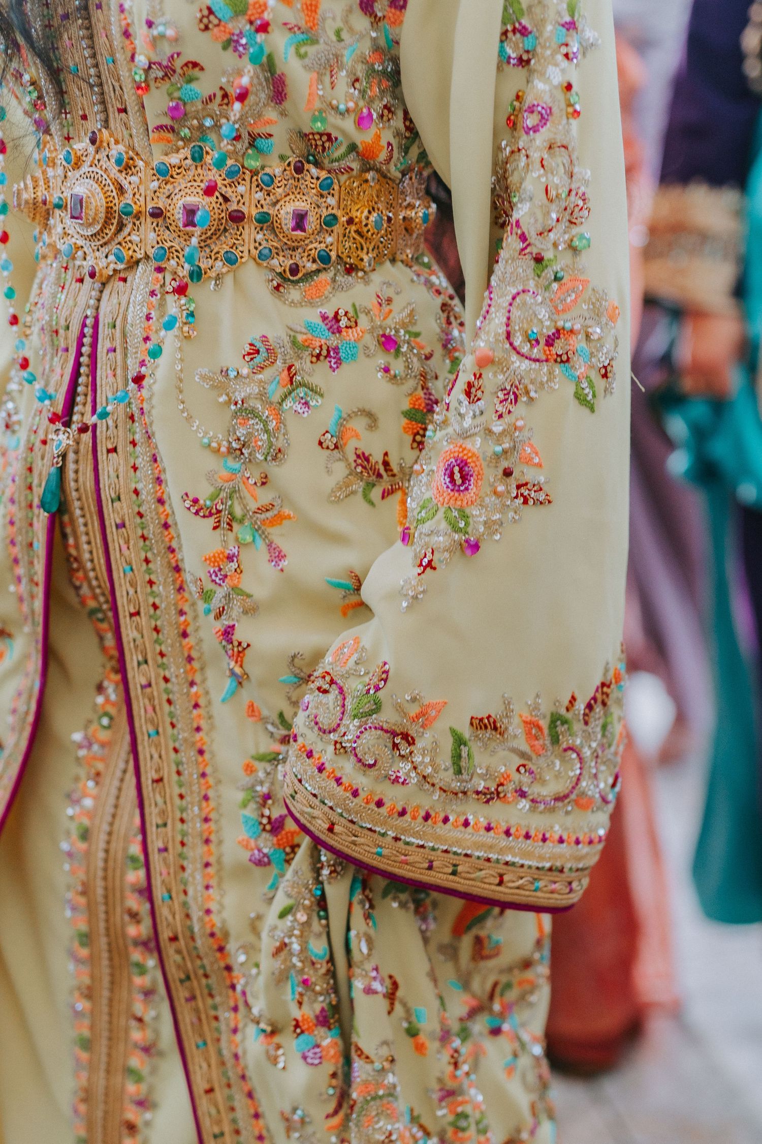 Detailed view of intricate floral embroidery on a cream-colored Moroccan dress.