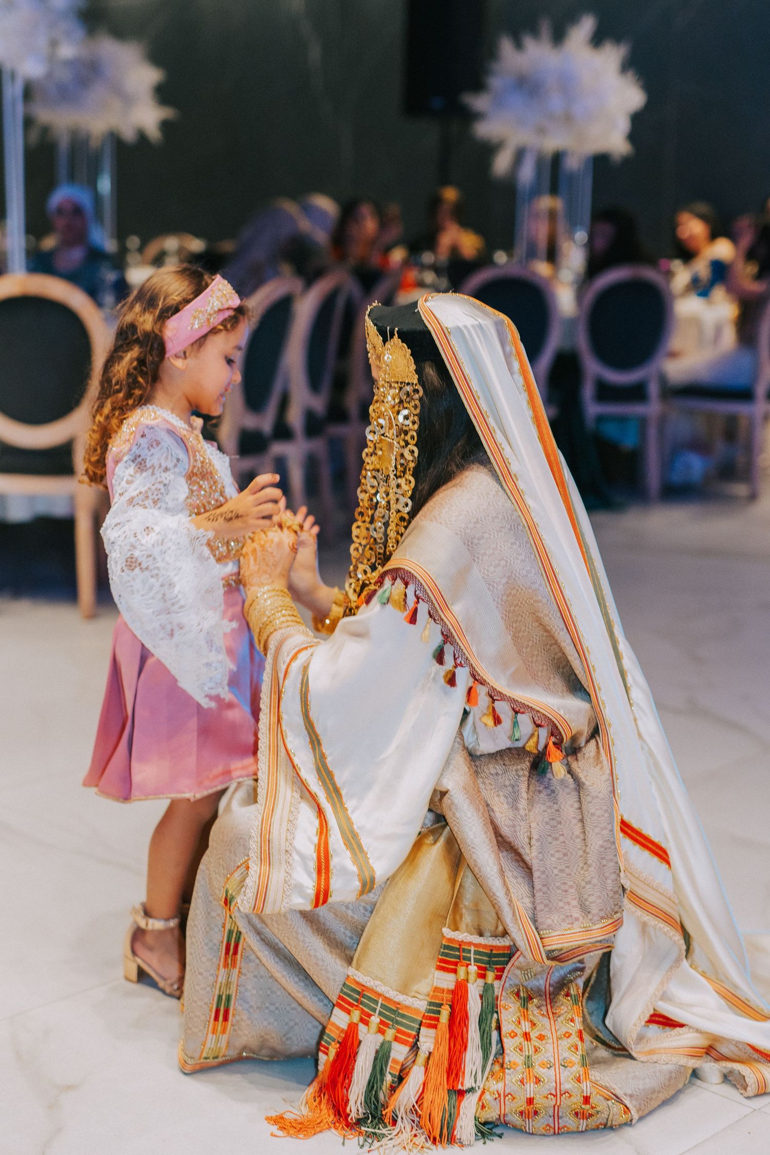 Traditional wedding ceremony scene with ornate white and gold attire and decorative elements.