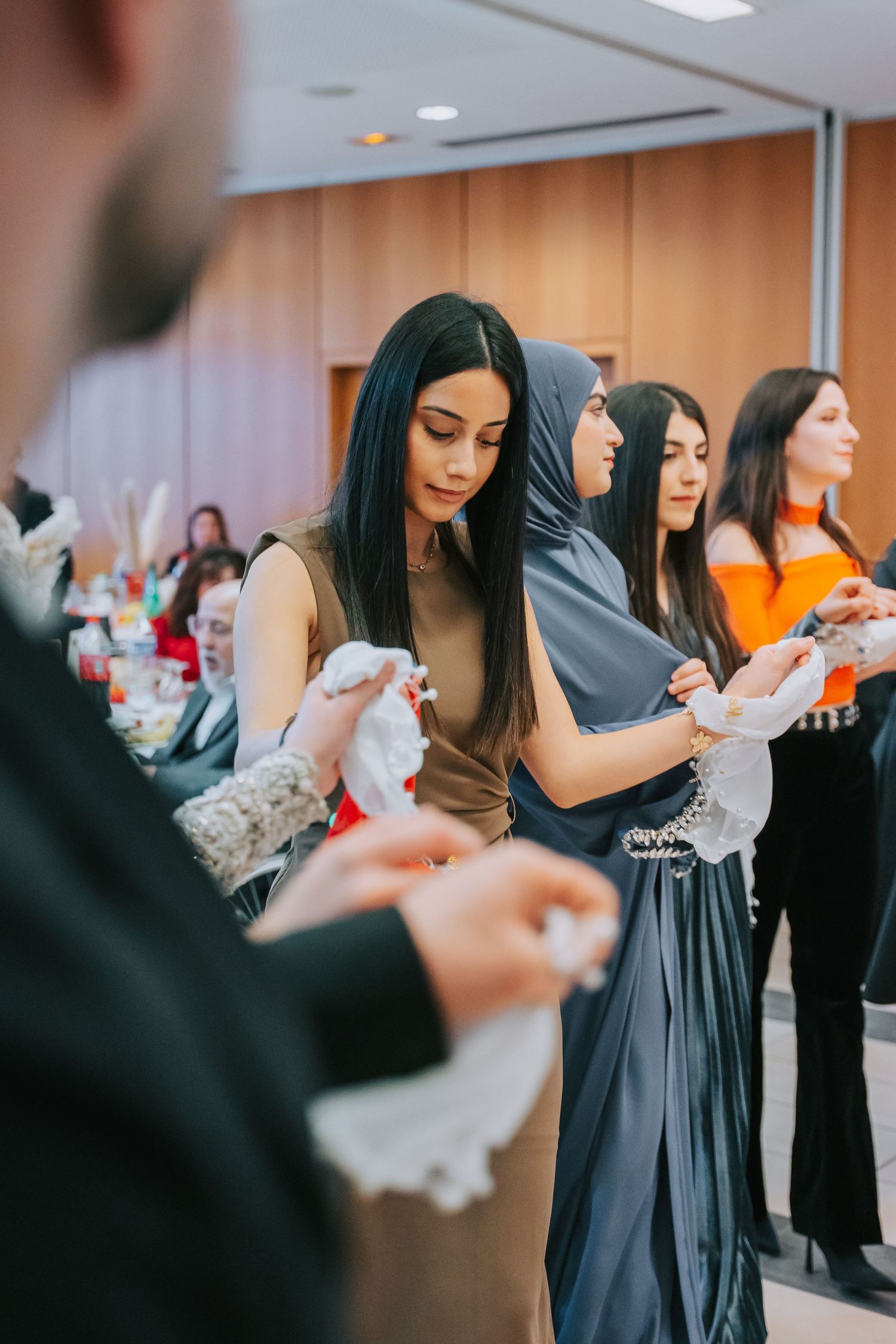 Group of elegantly dressed guests at a formal event gathered around a table.
