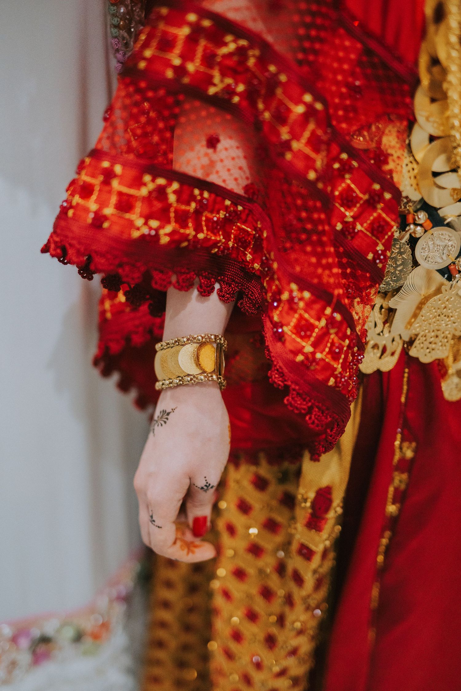 Close-up of intricate red and gold embroidered traditional wedding attire with jewelry.