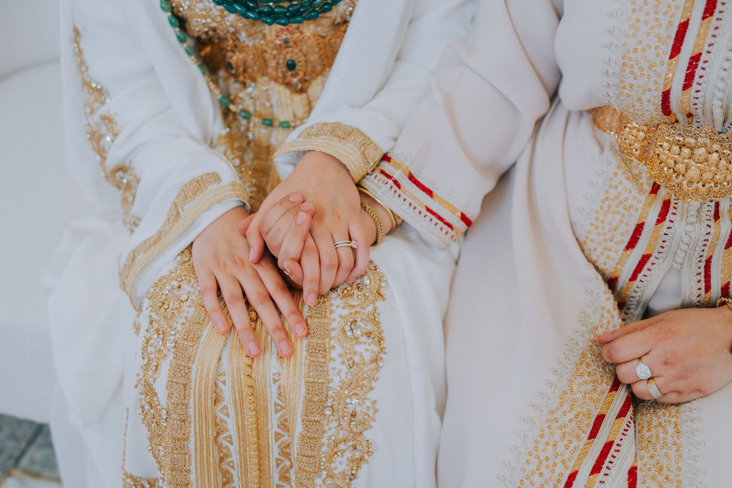 Close-up of hands wearing traditional Moroccan wedding attire with gold embellished details.