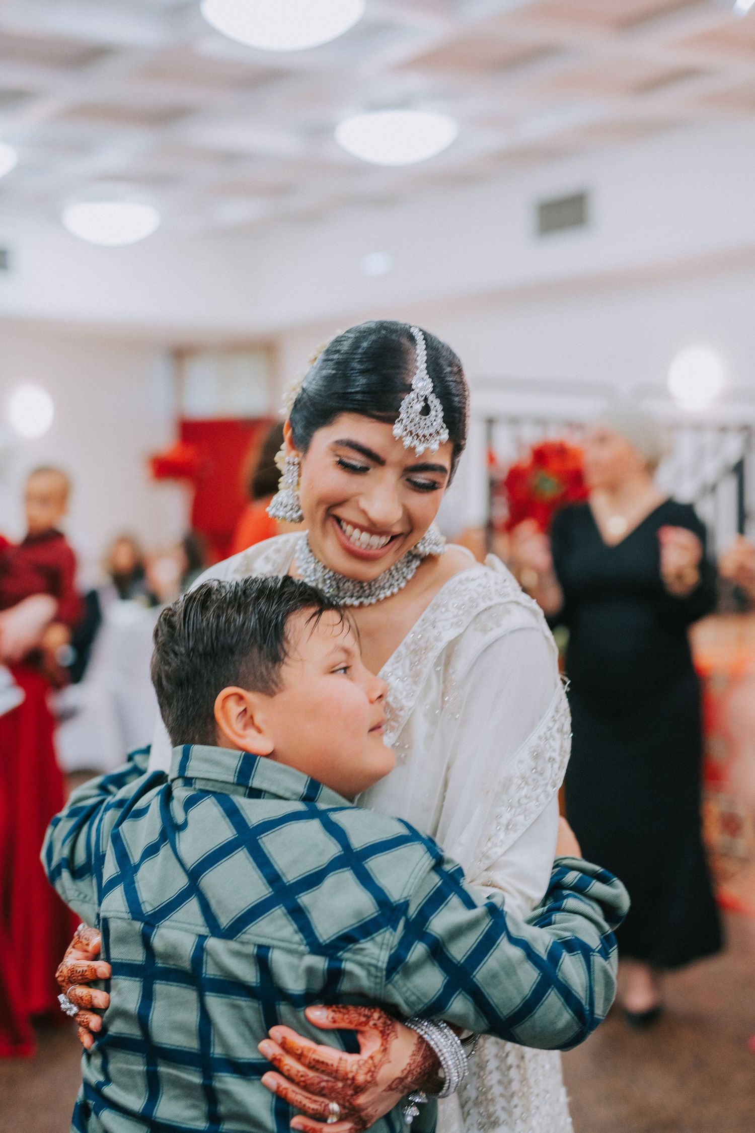 Emotional embrace shared during celebration in indoor venue with festive decorations.