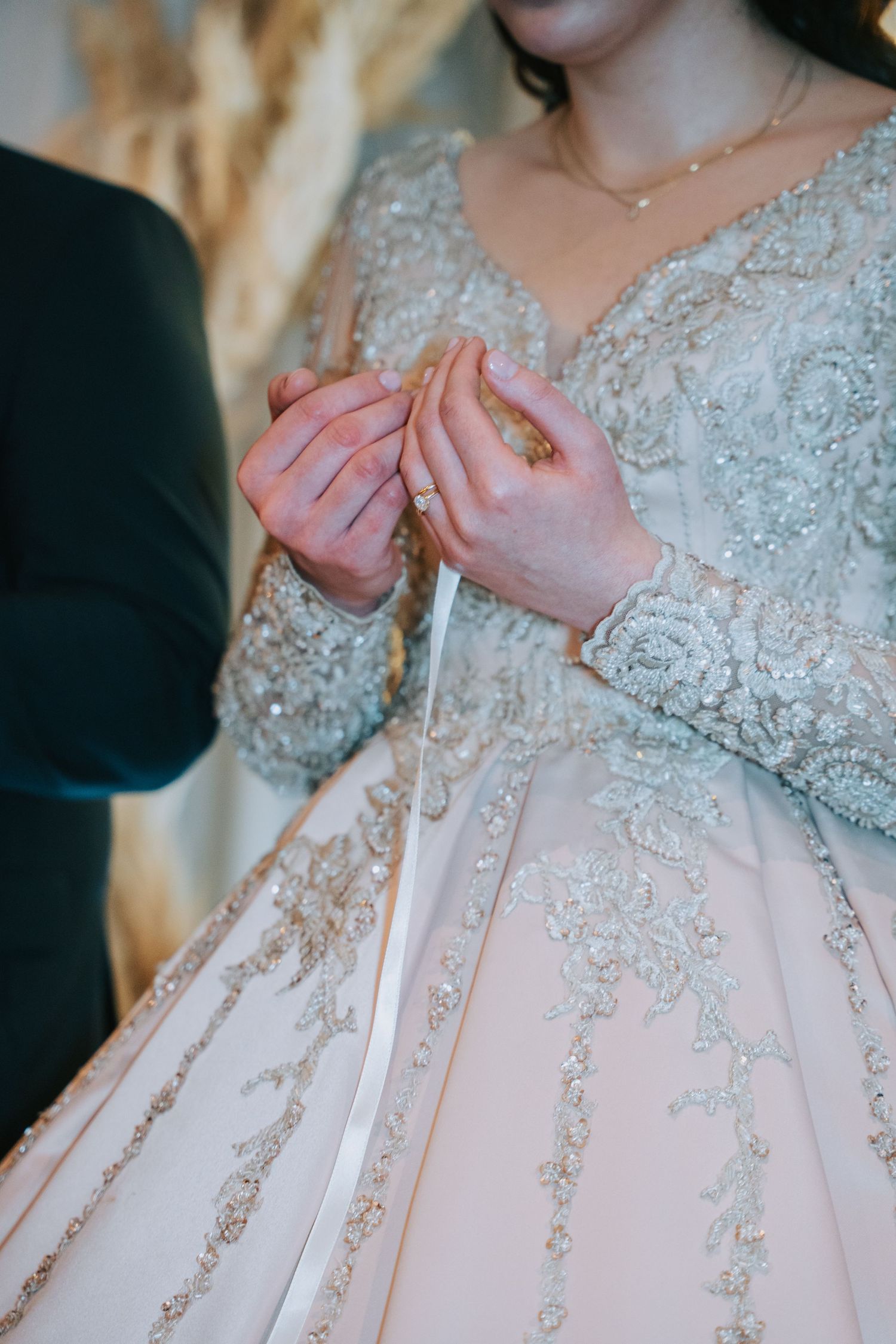 Detail shot of delicate lace and beading on a white wedding dress.