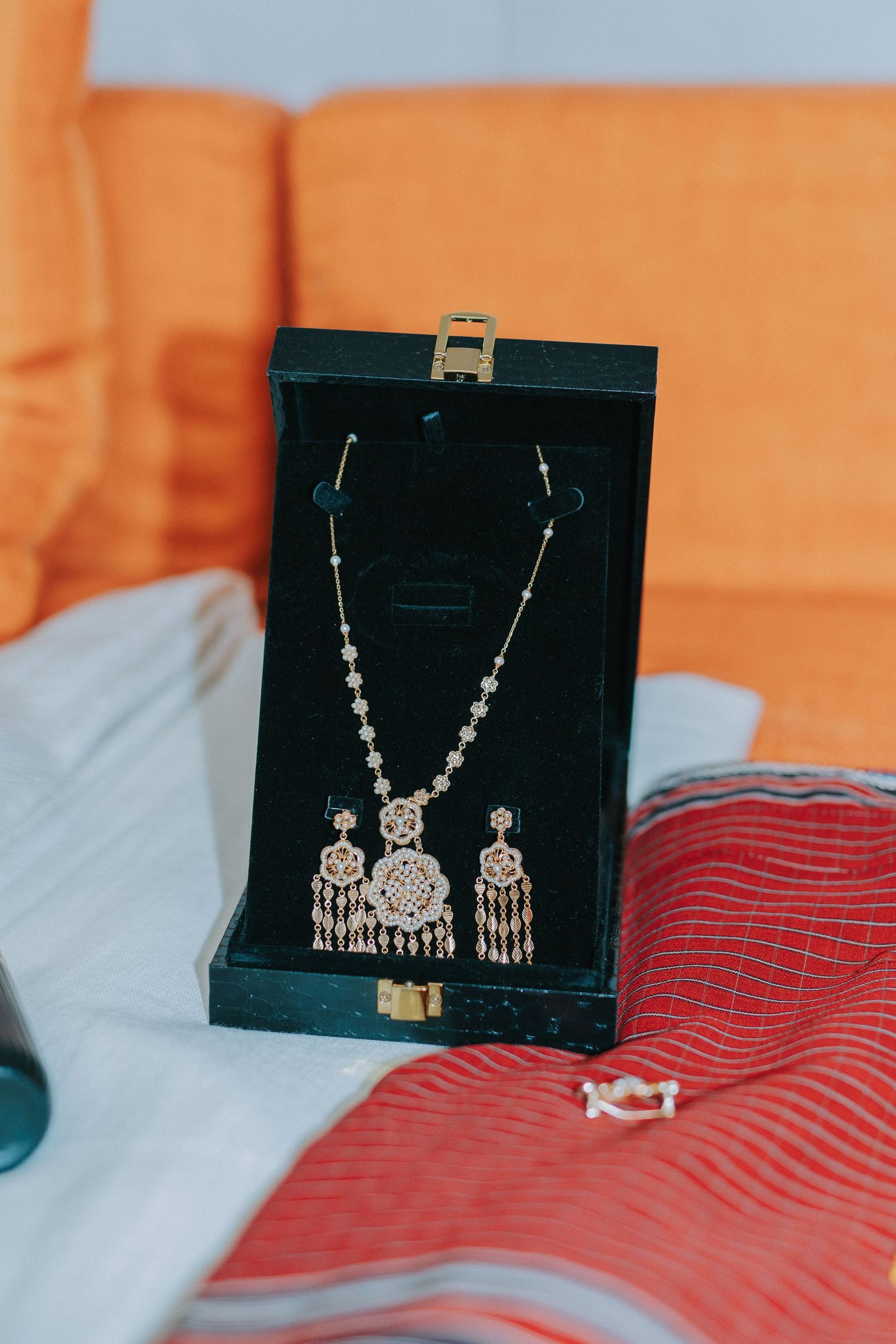 Ornate traditional Indian jewelry set with dangling elements displayed in a black velvet box.