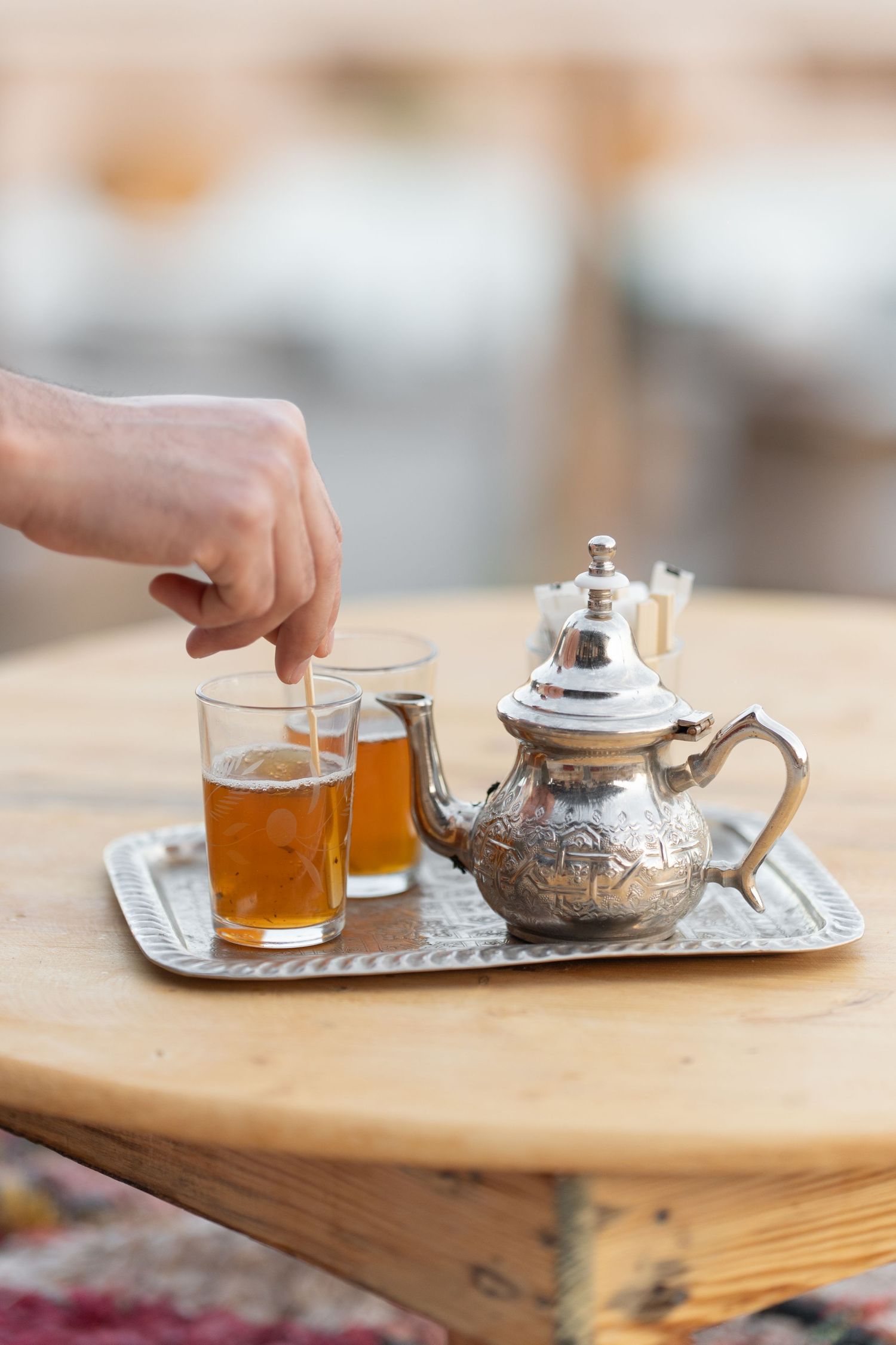 Traditional silver teapot and glasses of tea served on a wooden table.