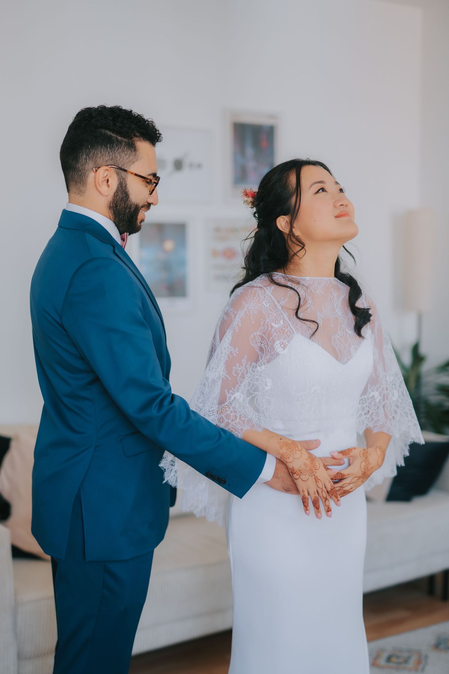 A couple shares an intimate moment on their wedding day, with the bride in a lace gown and groom in navy suit.