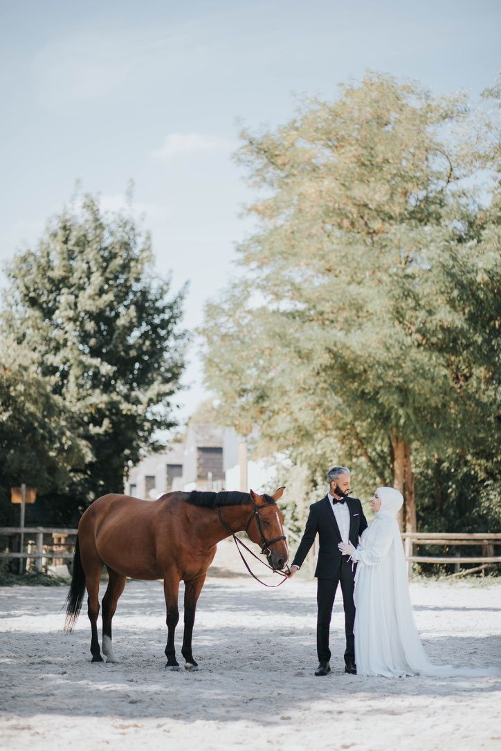 A wedding photo featuring a brown horse with a couple in formal attire.