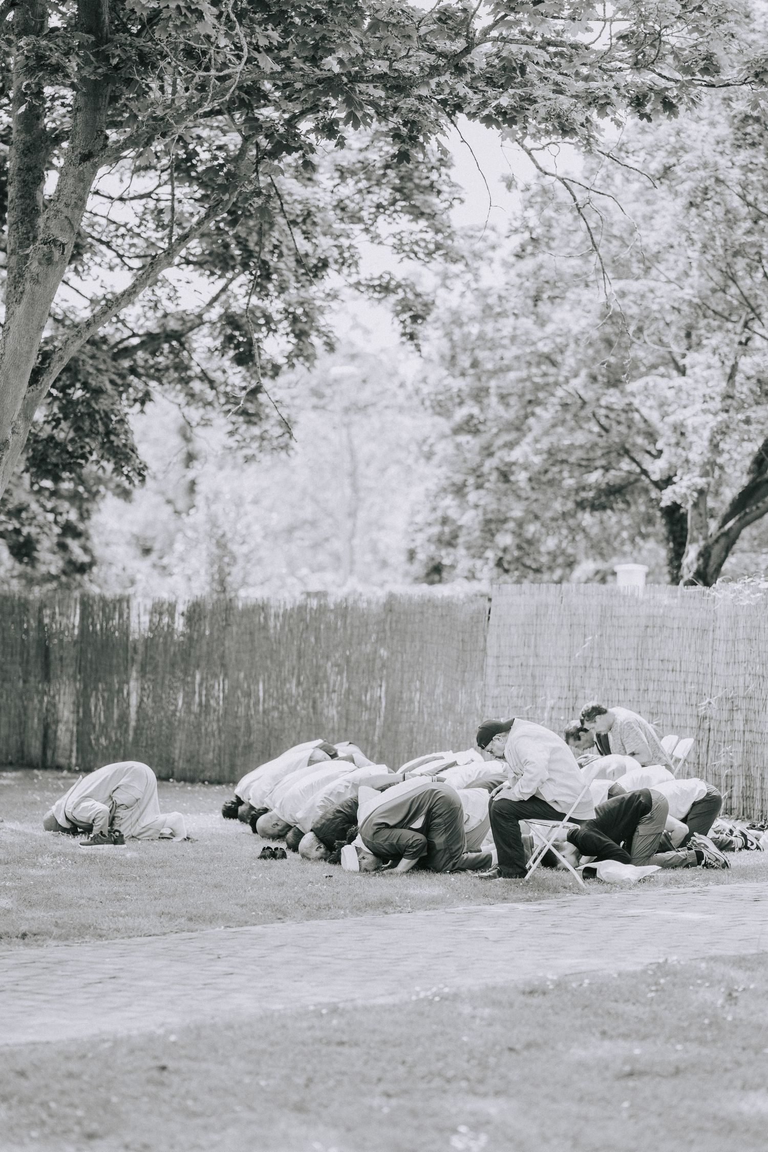 Group of people resting on grass in black and white vintage photograph.