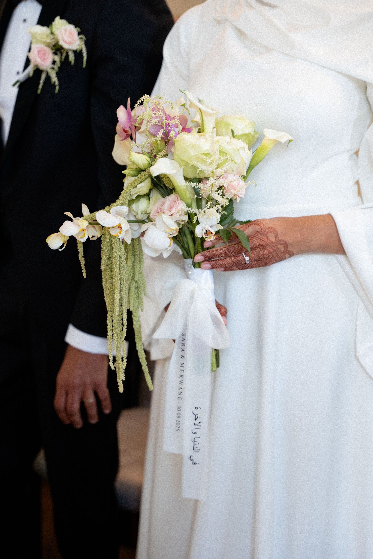 Elegant white bridal bouquet featuring soft pink and cream flowers with cascading amaranthus against a black background.
