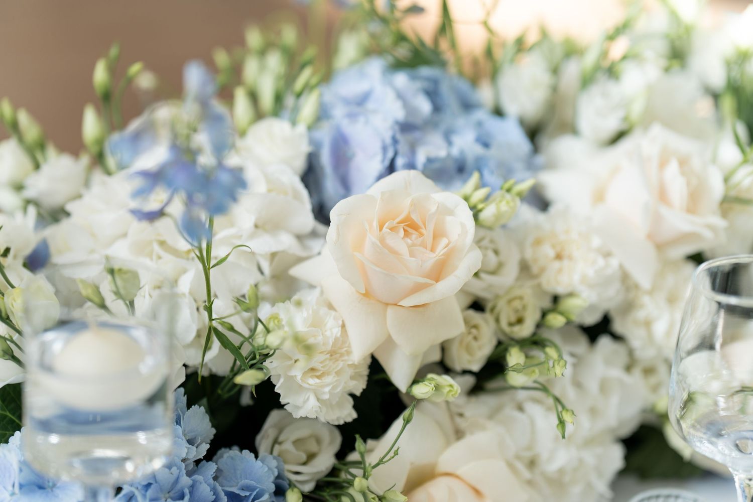 Elegant white and cream floral centerpieces with roses and hydrangeas arranged on a formal dining table.