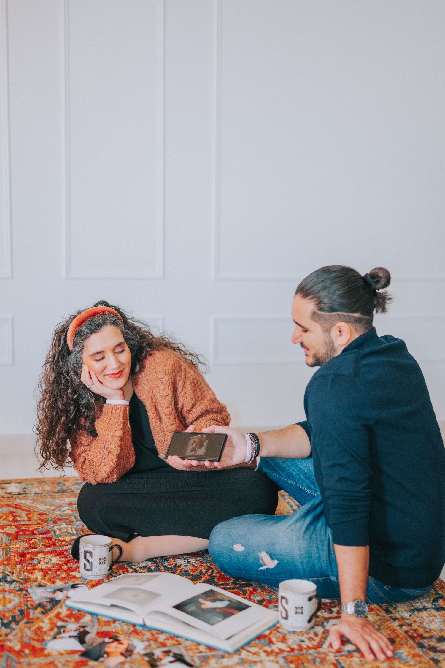 Two people sharing moments while looking through photos on a colorful rug.