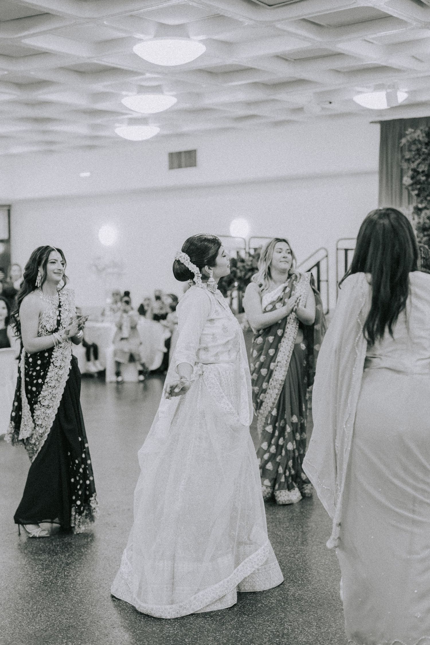 Wedding celebration in a banquet hall with guests in traditional South Asian attire dancing.
