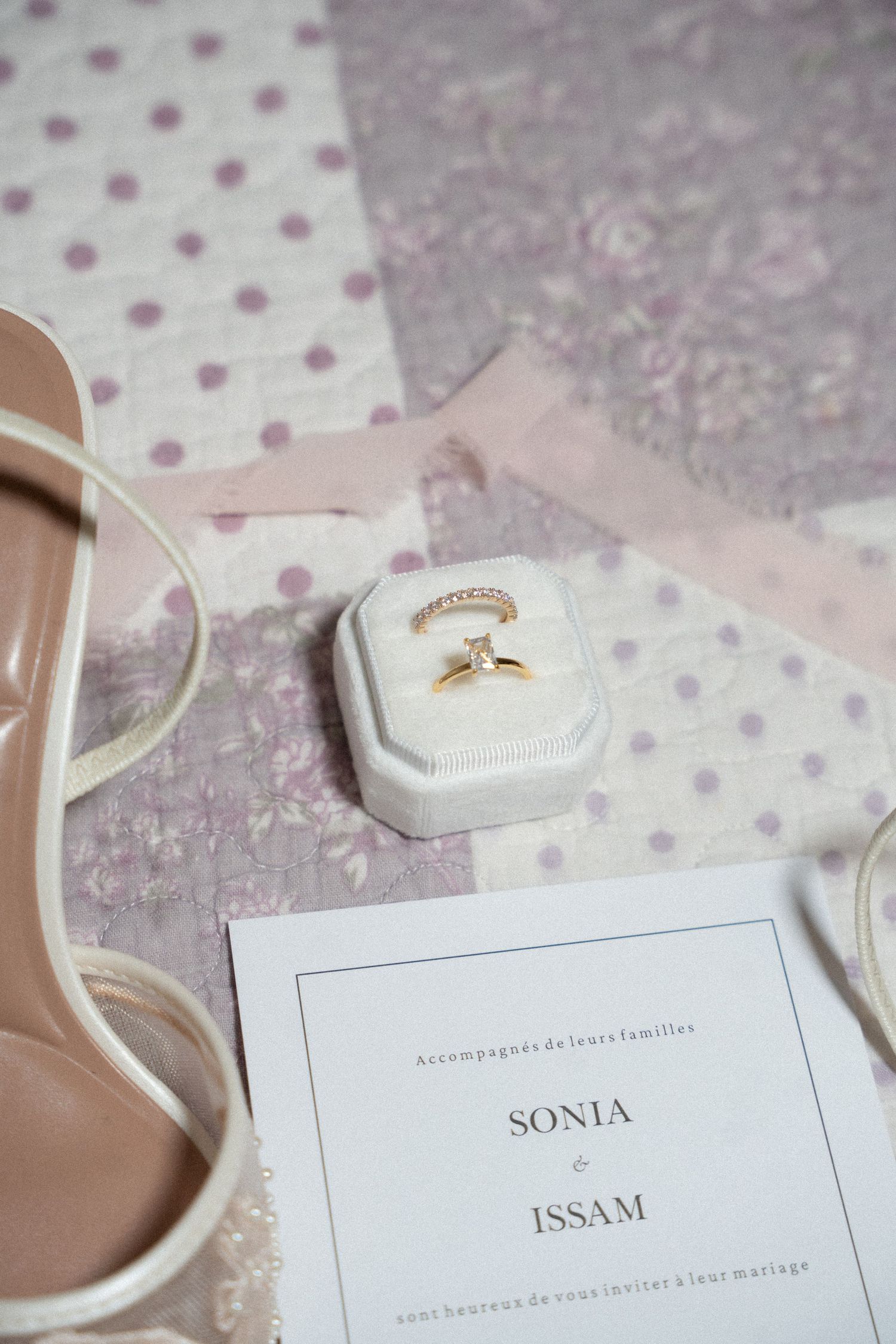 Wedding invitation cards and rings displayed on polka dot fabric with elegant styling and soft pastel colors.