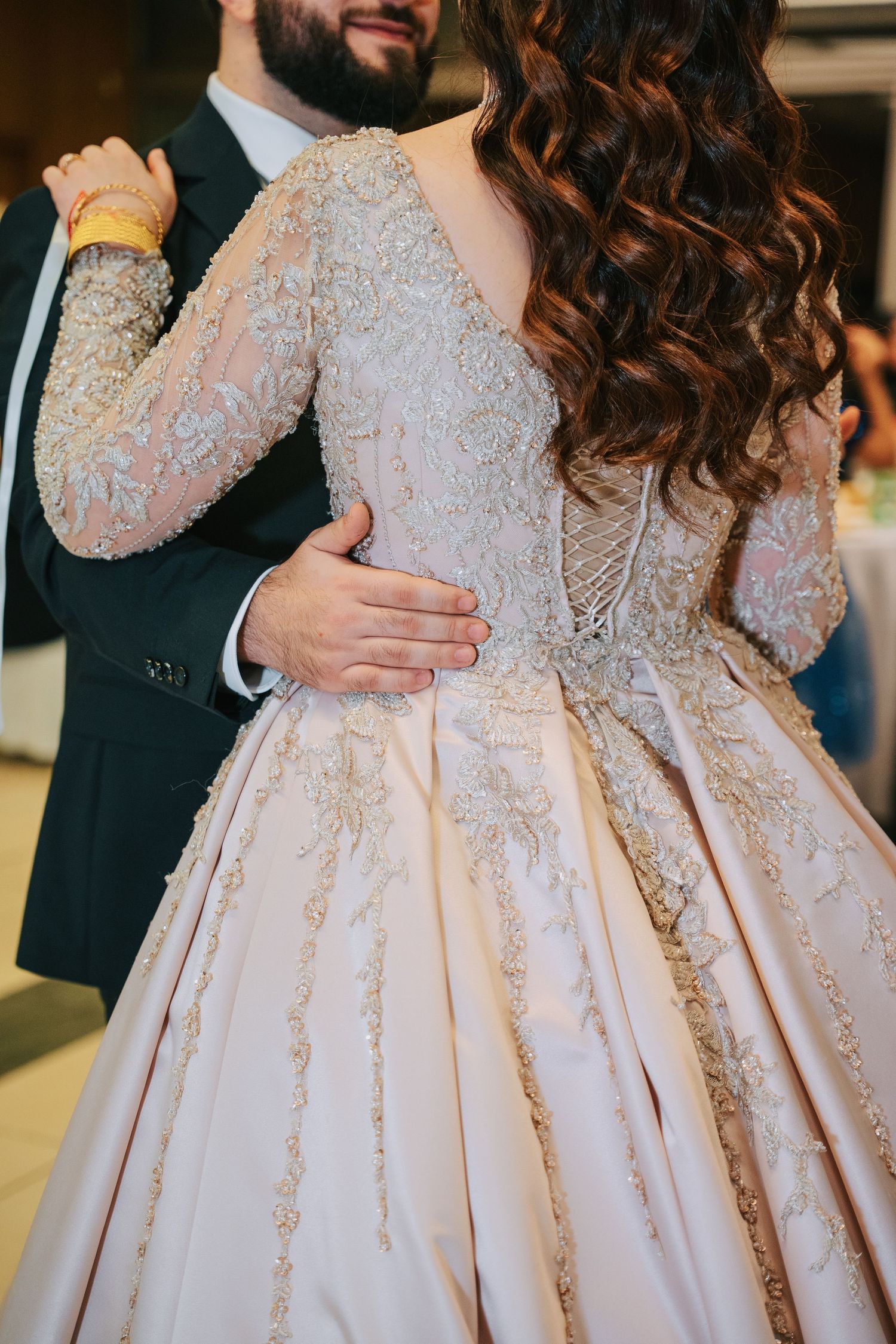 Close-up of an ornate lace wedding dress with beaded embellishments and full skirt.