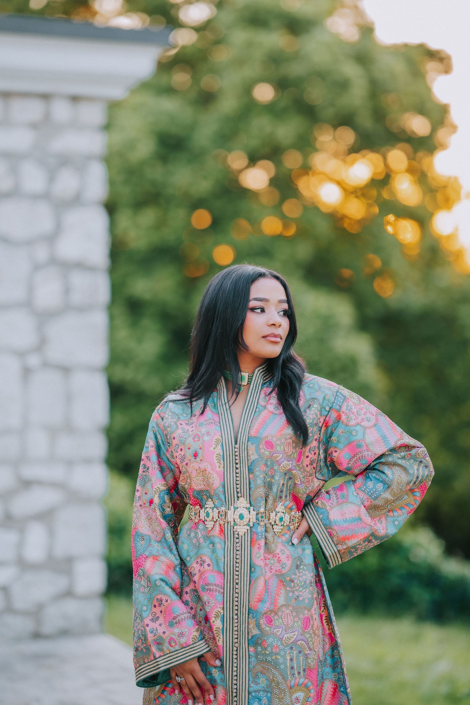 Portrait in a traditional floral Moroccan dress against a blurred garden background.
