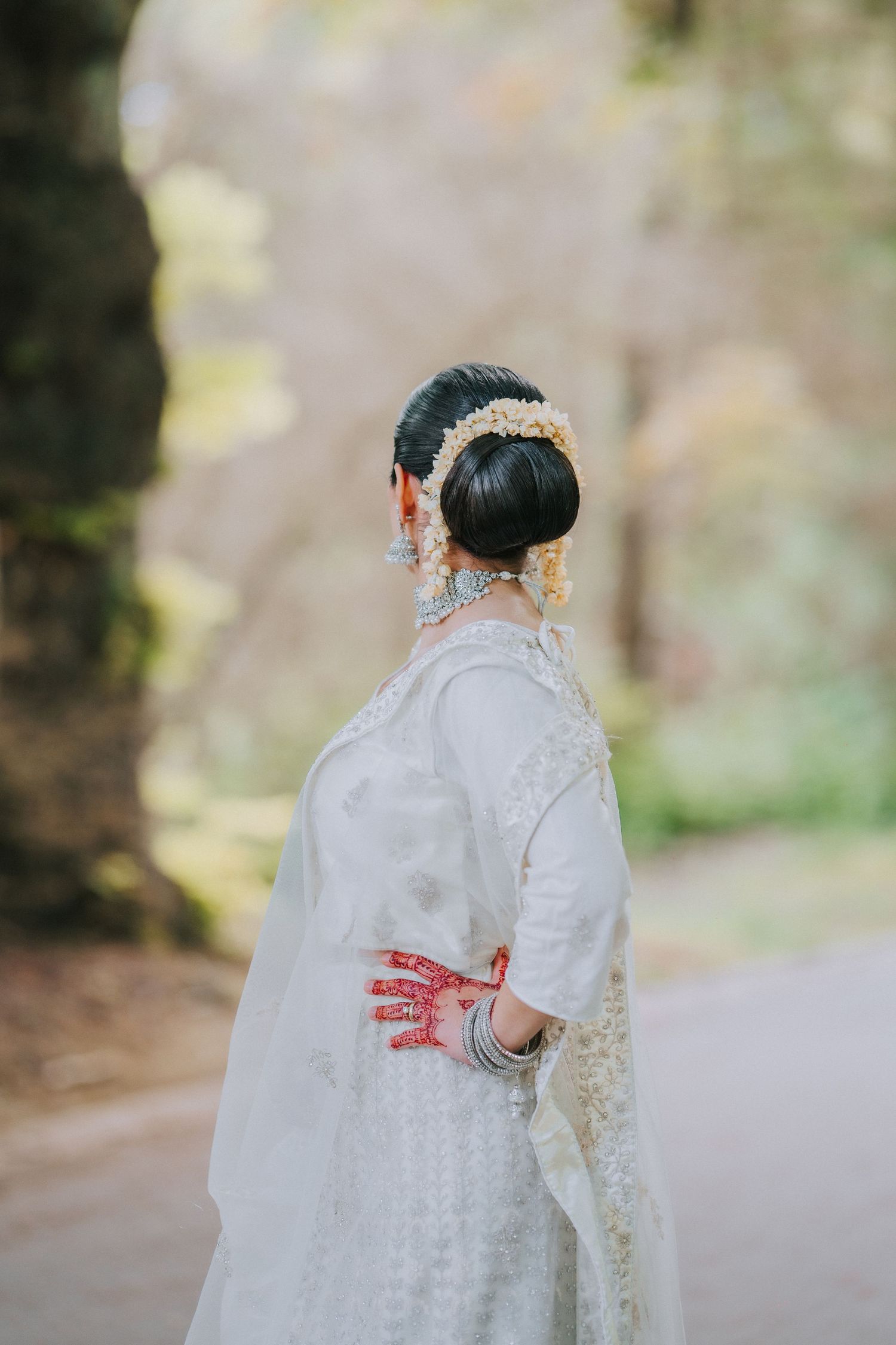 Traditional bridal outfit with white embroidered dress and mehndi-decorated hands.