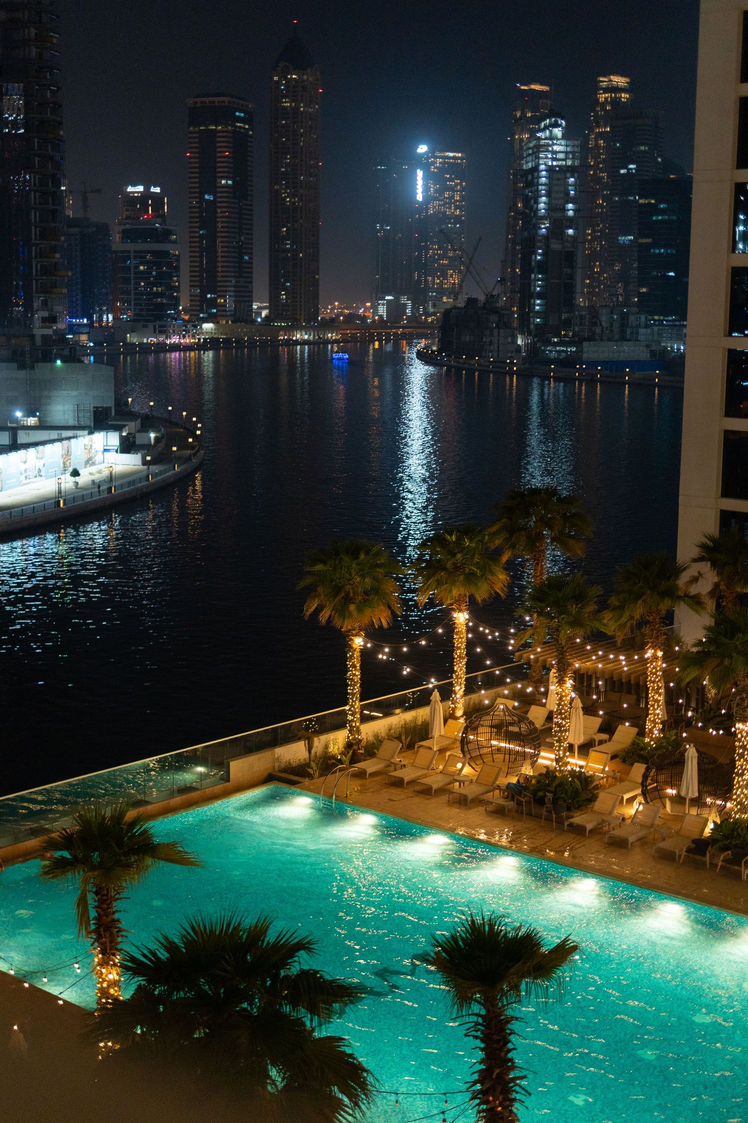 Luxurious illuminated pool overlooking Dubai's skyline and waterfront at night.