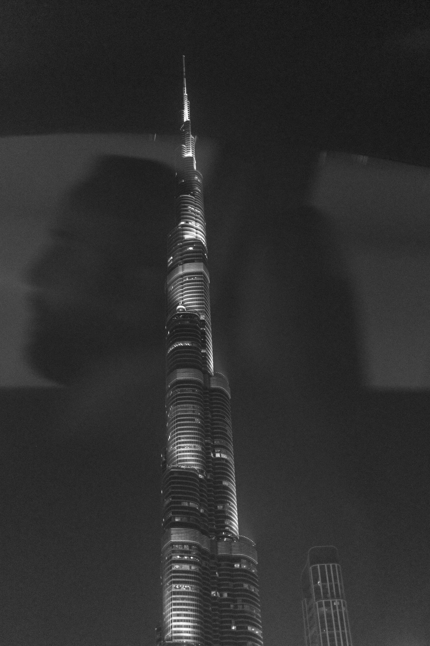 Black and white nighttime view of the illuminated Burj Khalifa tower in Dubai.