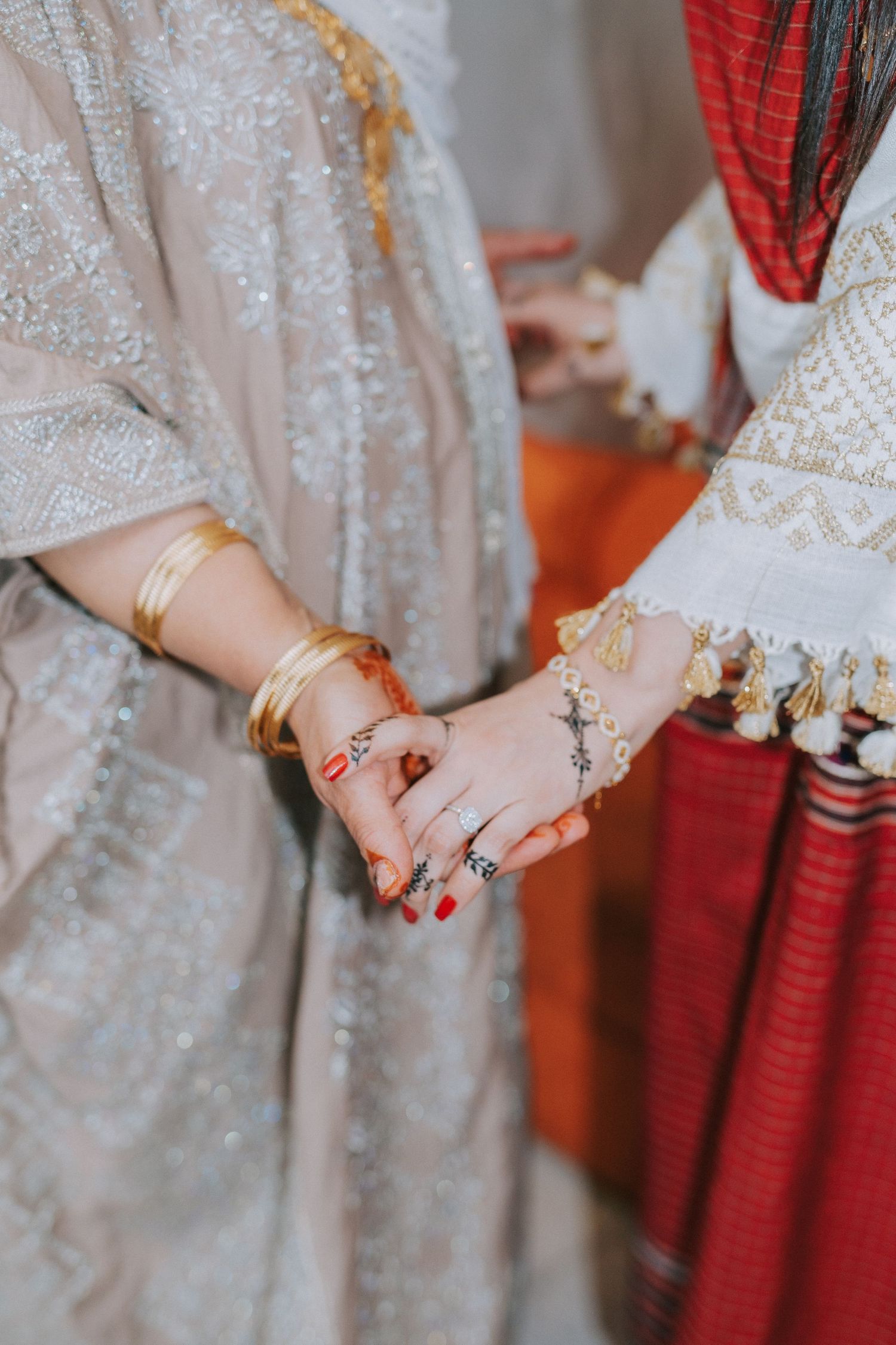 Close-up of hands wearing traditional Indian bangles and rings with intricate henna designs.