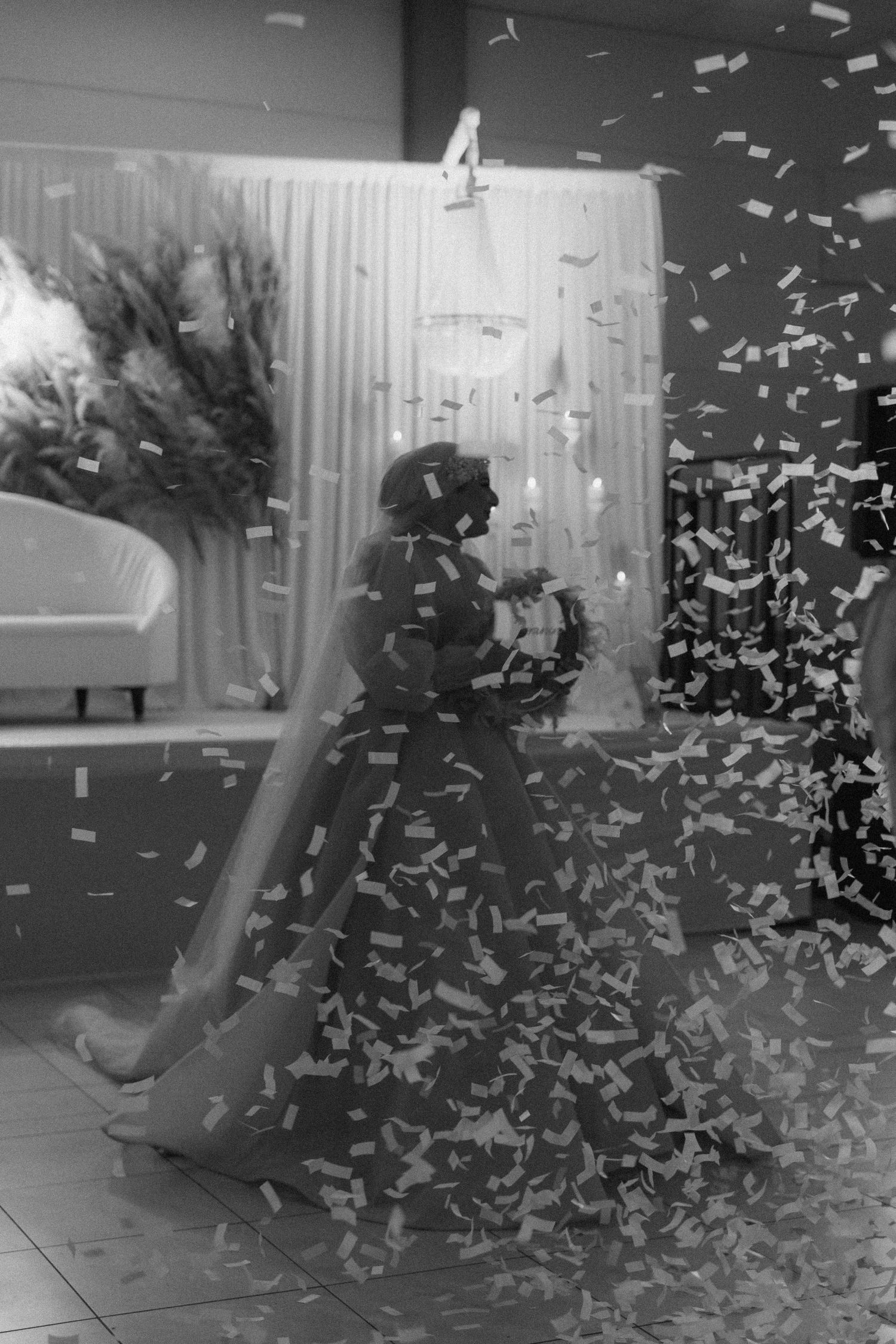 Black and white photo of celebration with confetti flying in dim lighting.
