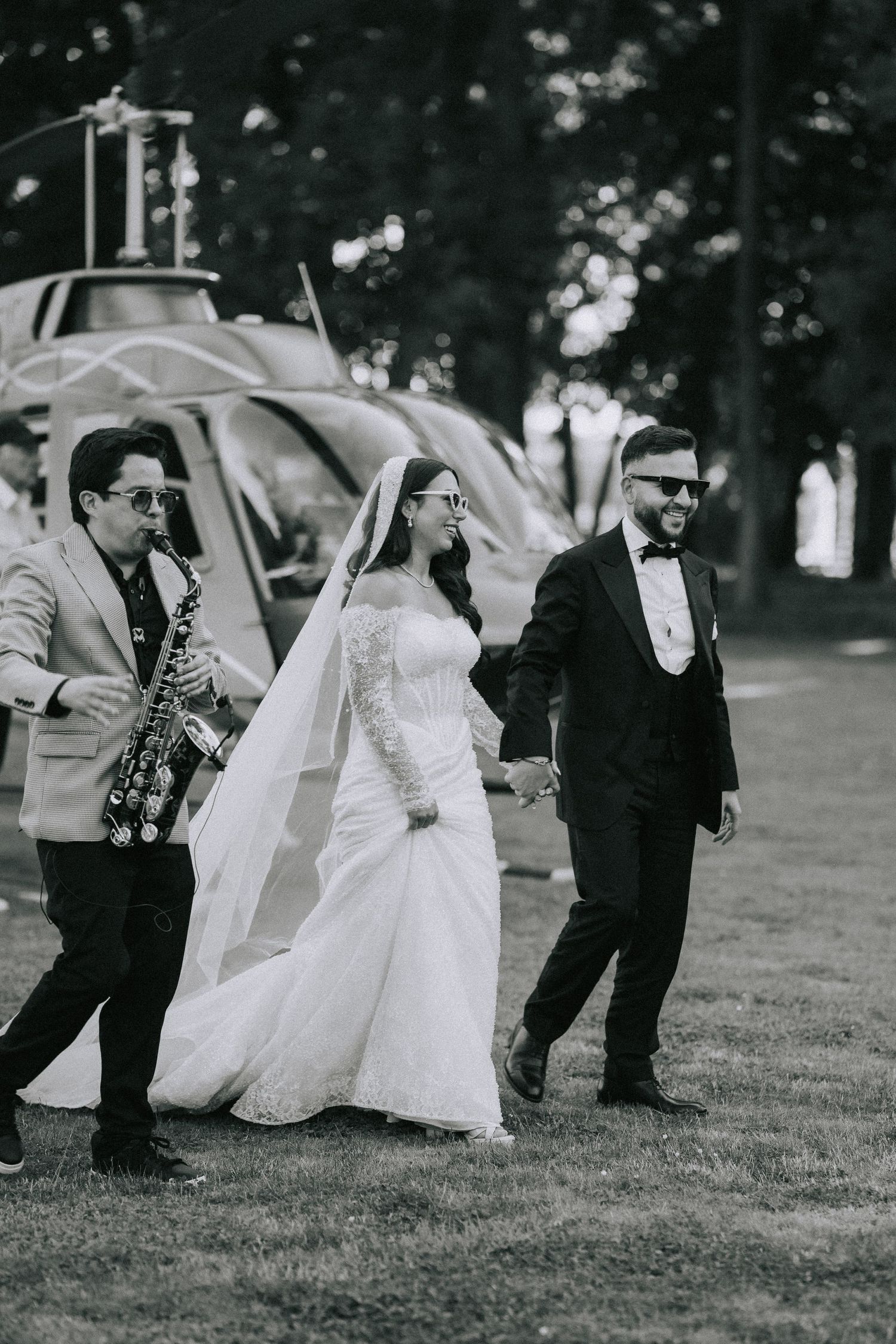 Black and white photo sequence showing wedding party dancing and celebrating on grassy lawn during outdoor reception.