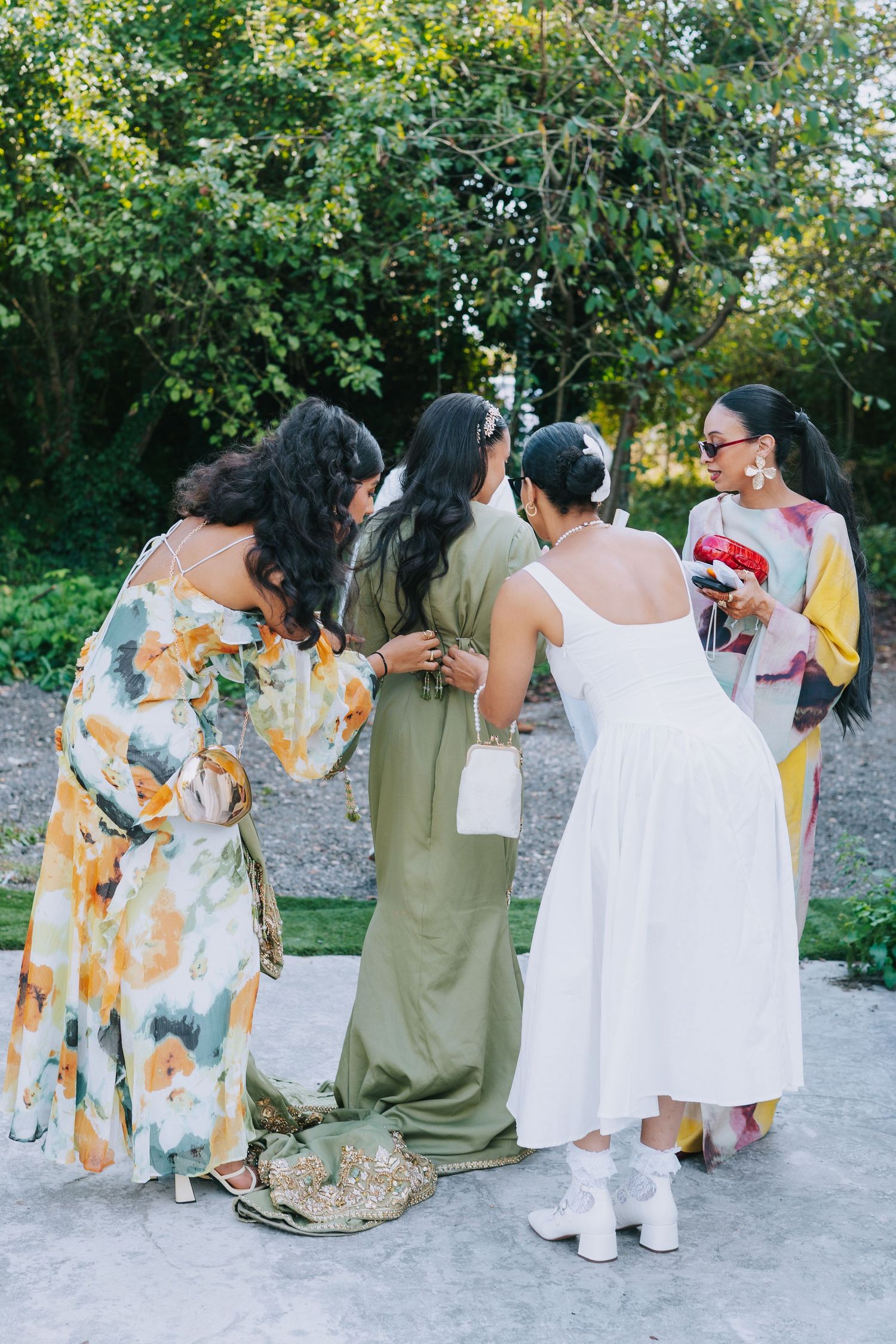 Group of guests in colorful floral dresses gathering at an outdoor event.