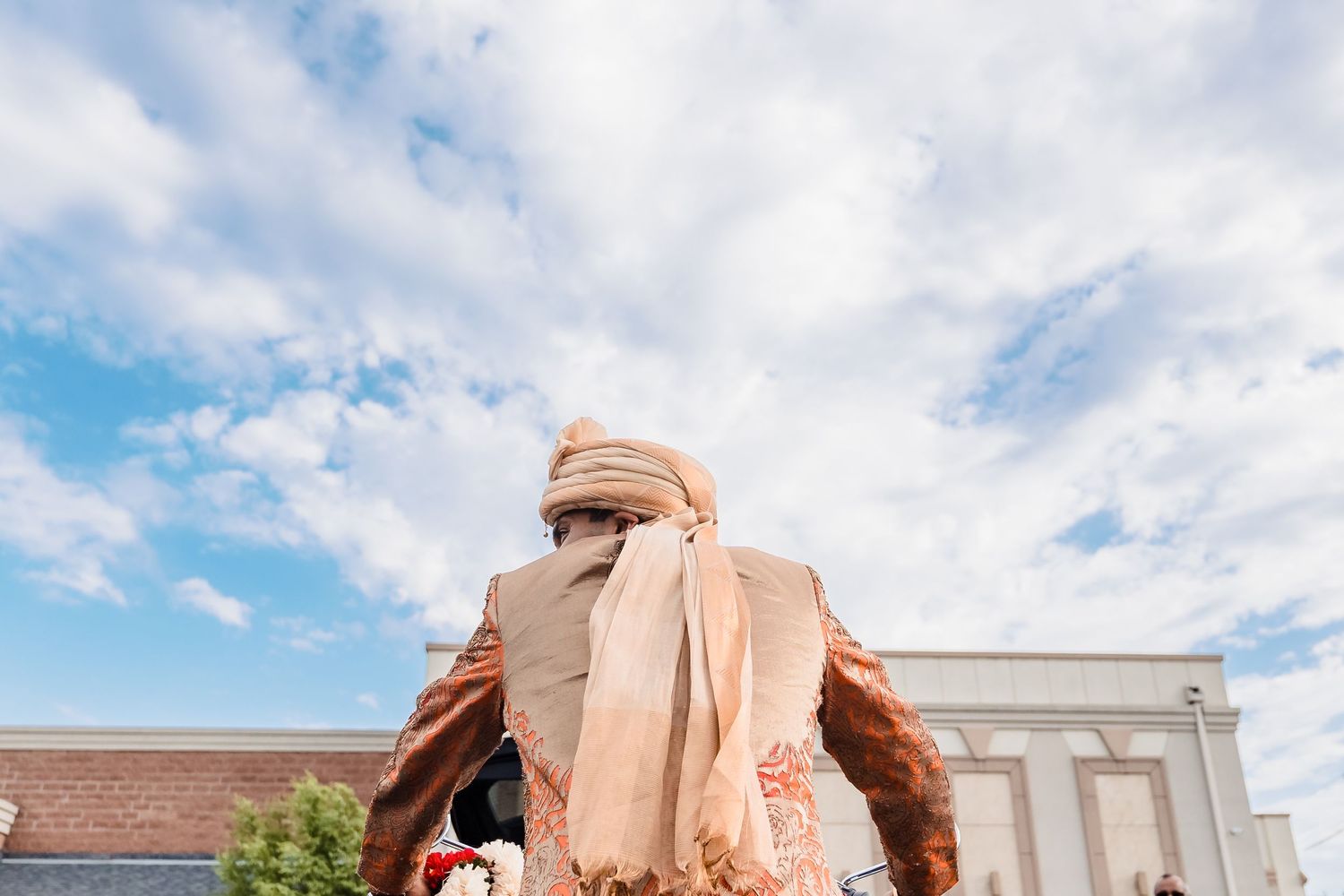 Low angle view of traditional Indian groom's turban against blue sky.