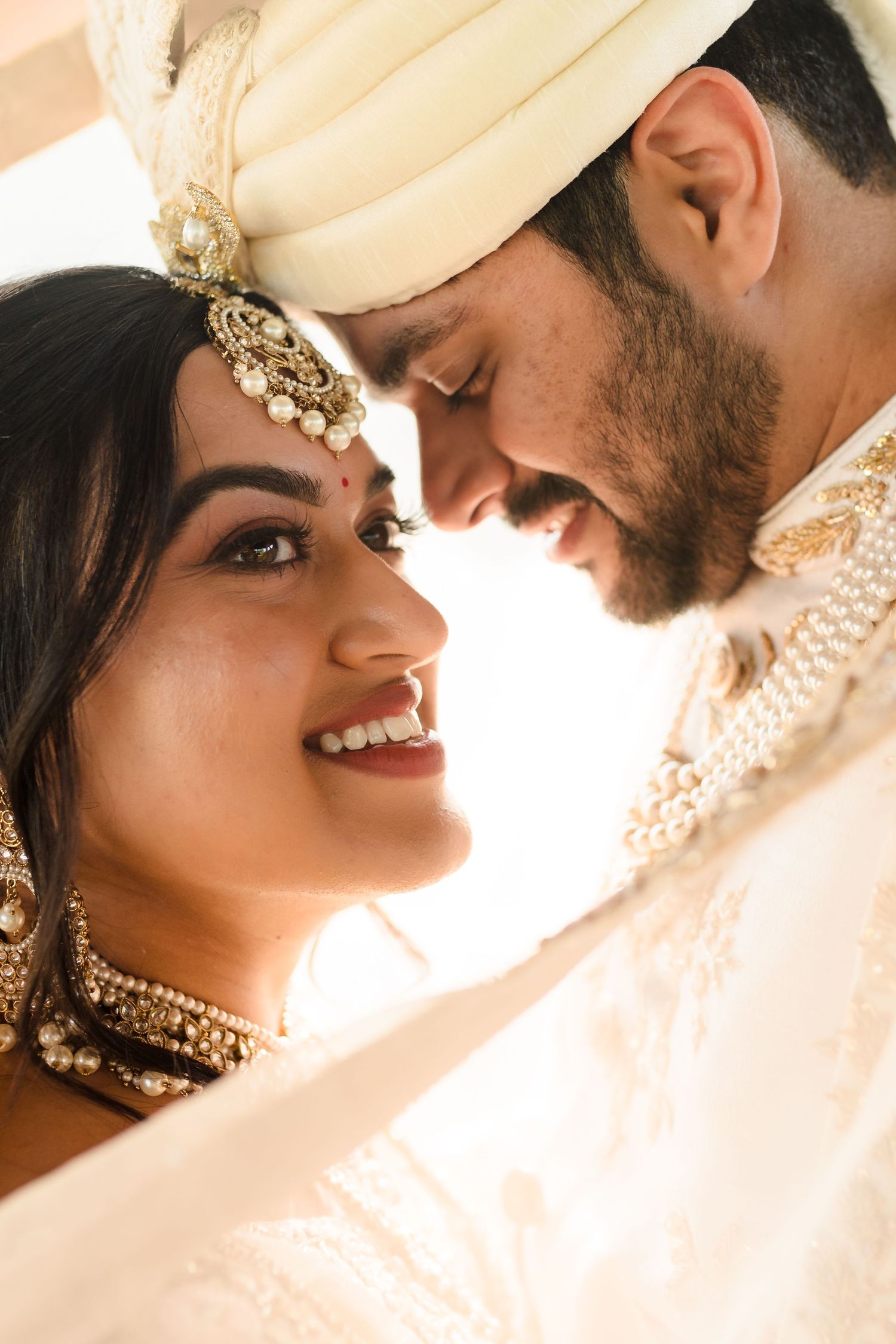 Intimate close-up of couple in traditional Indian wedding attire.