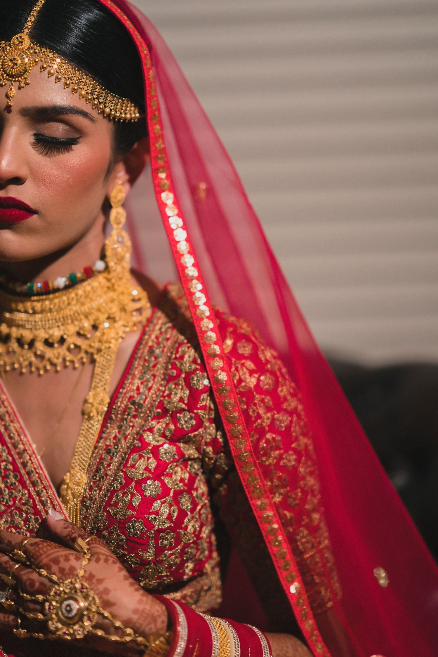 Traditional Indian bridal attire featuring ornate gold jewelry and a red embroidered dupatta.
