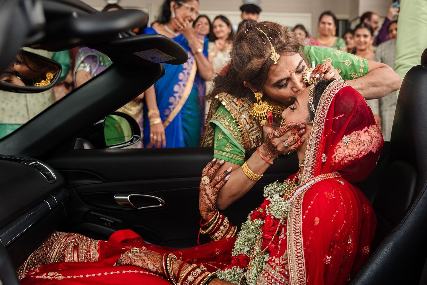 Traditional South Asian wedding ceremony with richly decorated bride in red attire seated in car.