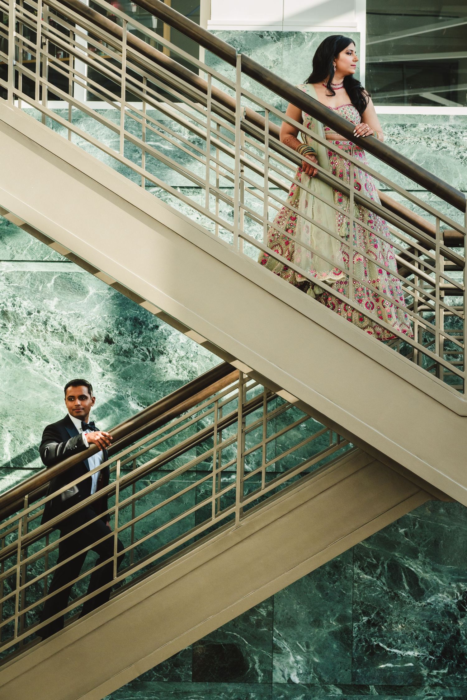 Creative wedding portrait on modern staircase with architectural elements and marble background.