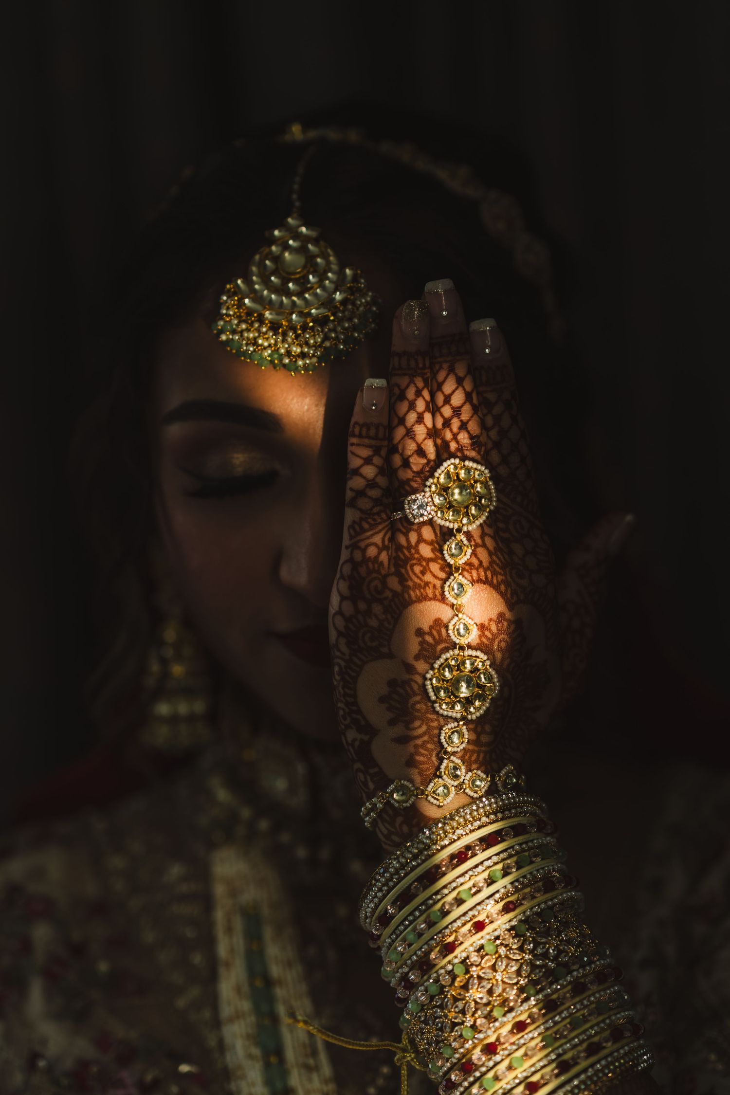 Close-up of intricate henna design and golden jewelry illuminated by warm light.