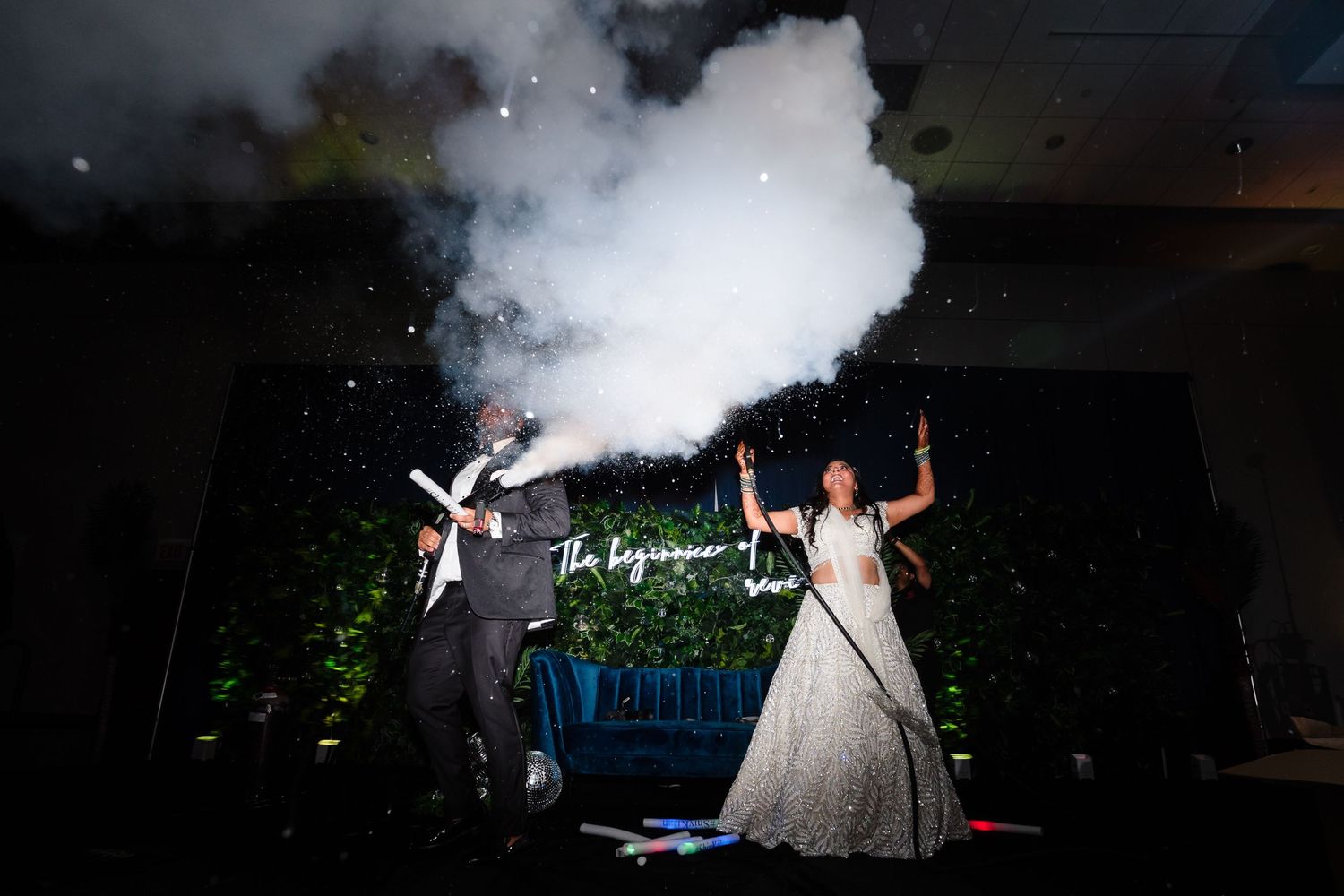 Dramatic nighttime celebration with smoke effects and neon lighting at an outdoor wedding reception.